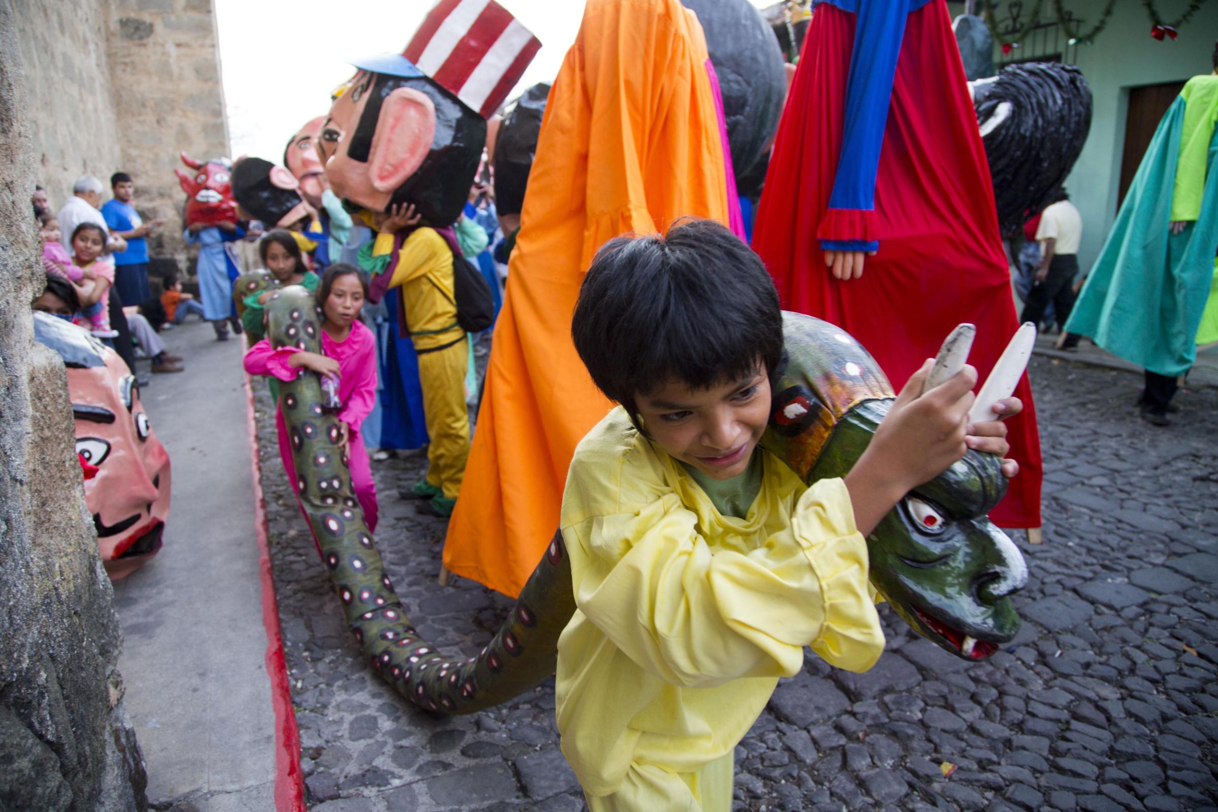 Children carry a snake made out of rags and paper mache as they take part in the traditional dance of "Los Gigantes," or "The Giants," during Christmas celebrations on Christmas Eve in Antigua Guatemala on Dec. 24, 2014.