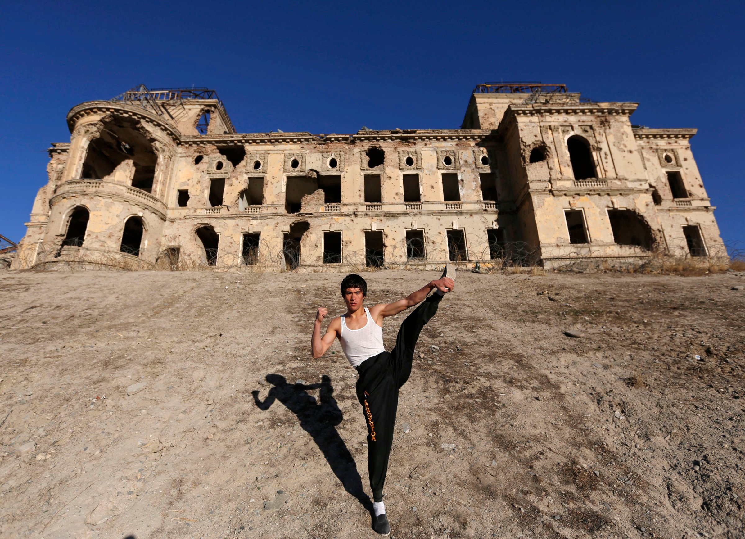 Abbas Alizada, who calls himself the Afghan Bruce Lee, poses for the media in front of the destroyed Darul Aman Palace in Kabul