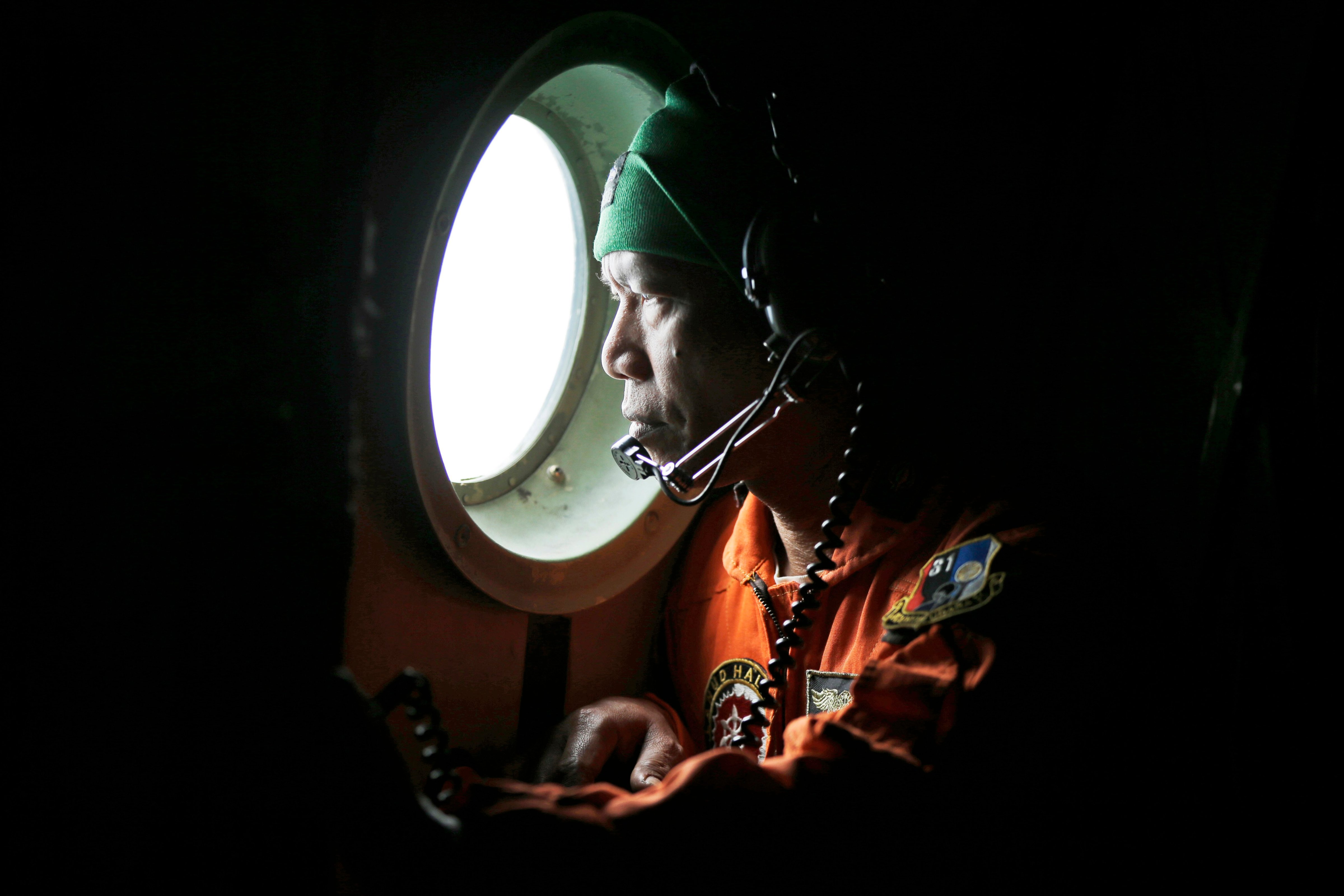 A crew of an Indonesian Air Force C-130 airplane of the 31st Air Squadron looks out of the window during a search operation for the missing AirAsia flight 8501 jetliner over the waters of Karimata Strait in Indonesia on Dec. 29, 2014.
