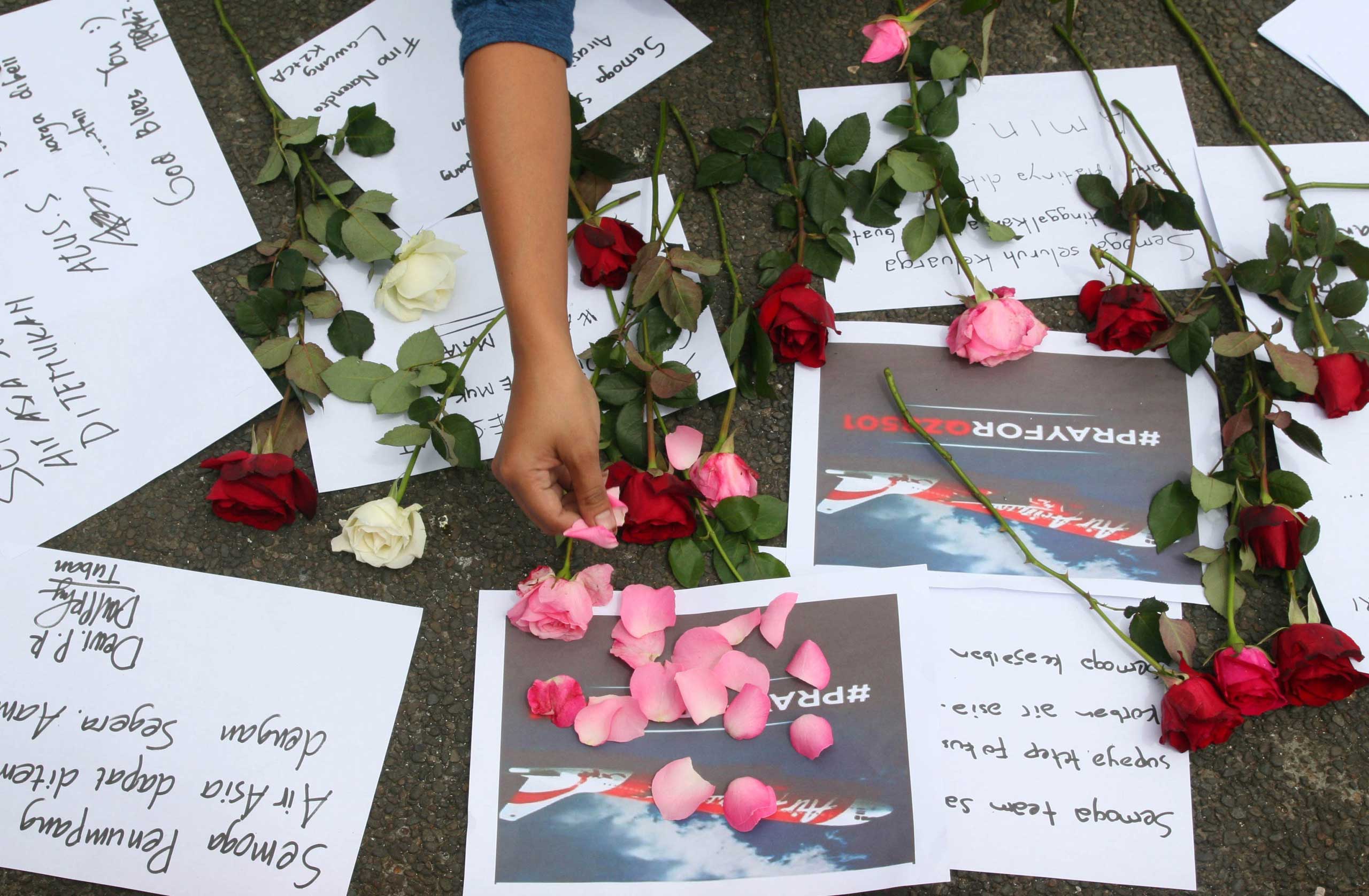 An Indonesian woman lays flowers as people pray for passengers of the missing AirAsia flight QZ8501 in Malang, East Java, Indonesia on Dec. 30, 2014.
