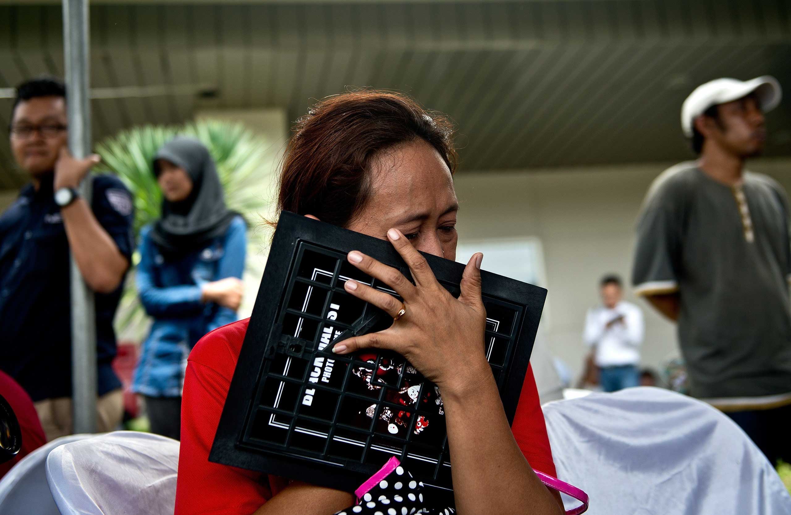 An Indonesian woman breaks down while holding a family picture of passengers onboard the missing AirAsia flight QZ8501, outside the crisis-centre set up at Juanda International Airport in Surabaya, Indonesia on Dec. 29, 2014.