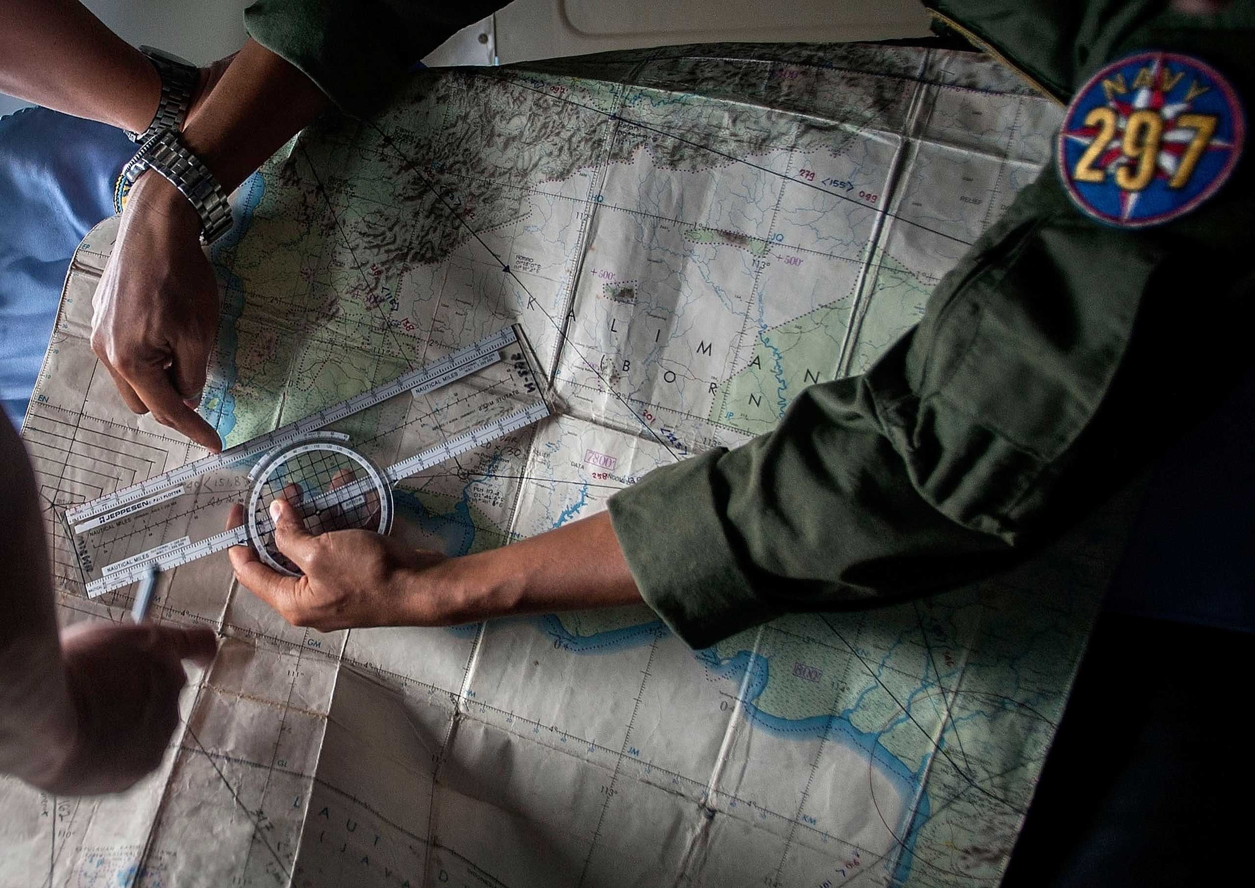 Indonesian Army personnel read a map during a search and rescue operation for missing AirAsia flight QZ8501, over the waters of the Java Sea on Dec. 29, 2014.