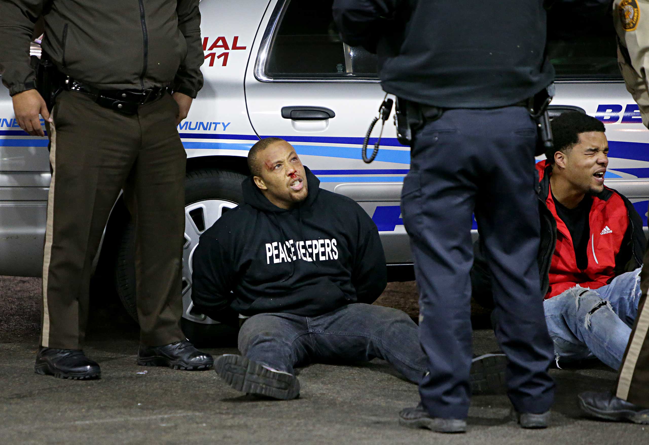 Police try to control a crowd on Dec. 24, 2014, on the lot of a gas station following a shooting in Berkeley, Mo.