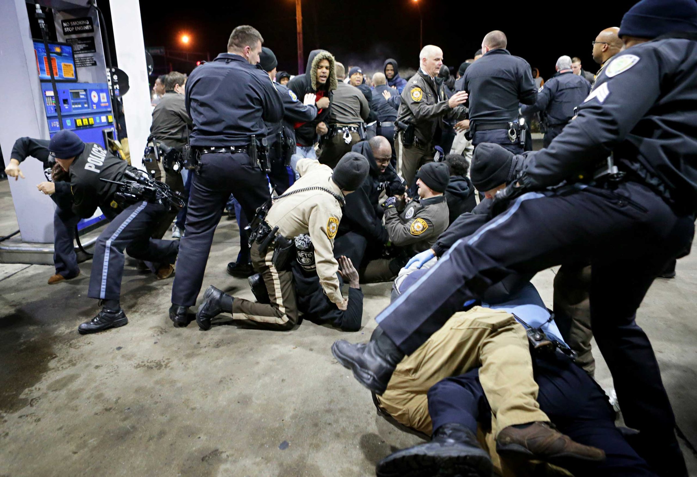 Police try to control a crowd on Dec. 24, 2014, on the lot of a gas station following a shooting Tuesday in Berkeley, Mo.