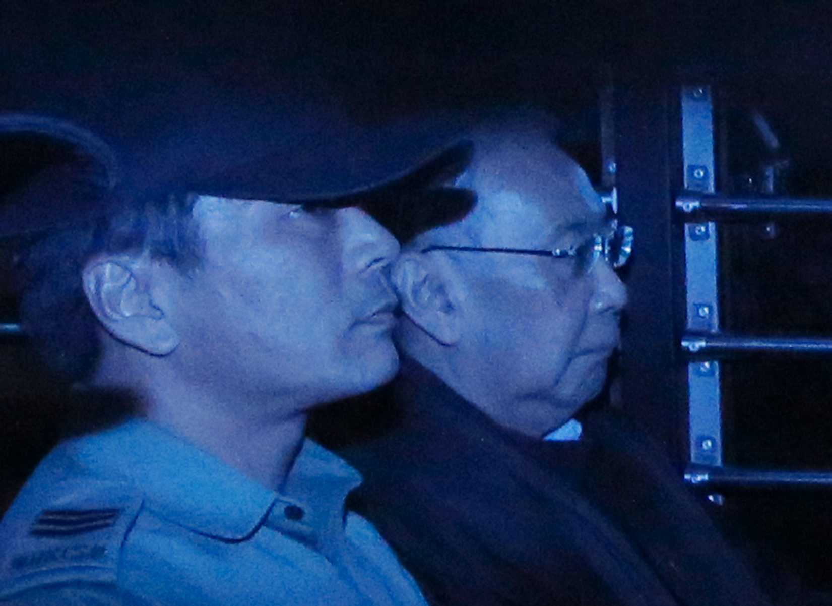 In this photo taken through a tinted glass, former Hong Kong Chief Secretary Rafael Hui, right, is escorted by a staff member from Hong Kong Correctional Services inside a van outside the High Court in Hong Kong on Dec. 19, 2014 (Vincent Yu—AP)