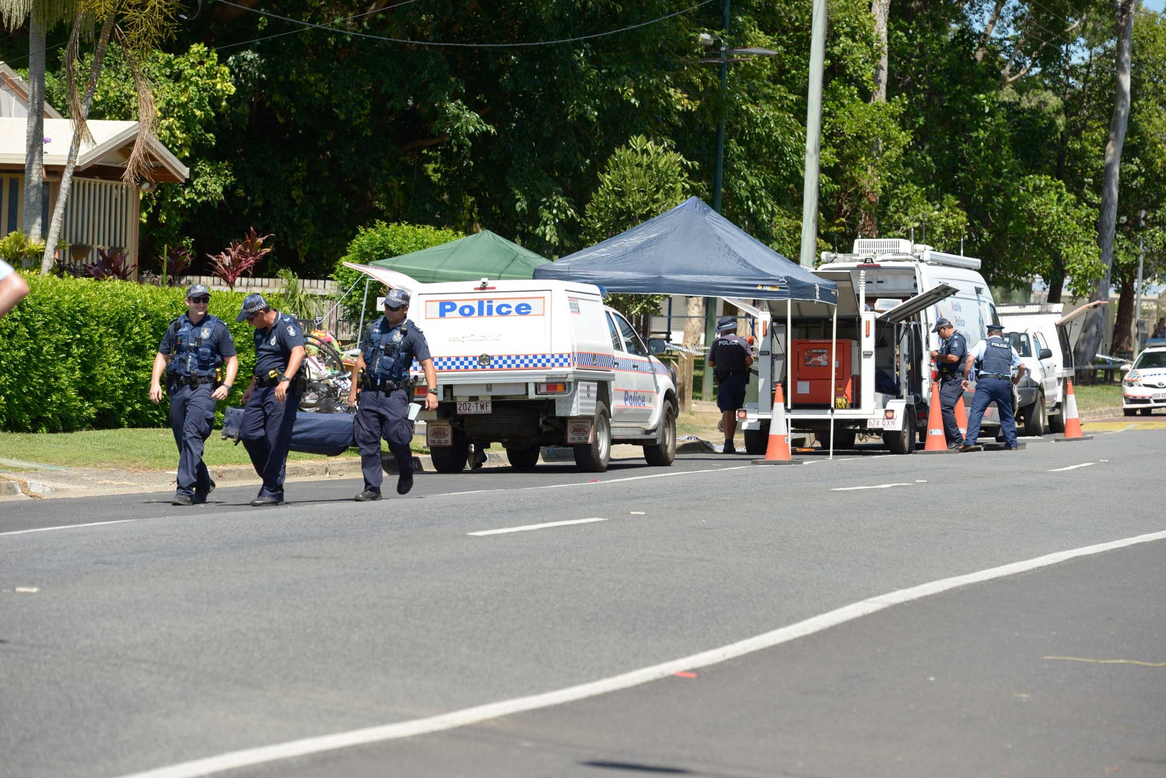 Police carry equipment near a road block outside a house where eight children have been found dead  in the Cairns suburb of Manoora, Australia, Friday Dec. 19, 2014.