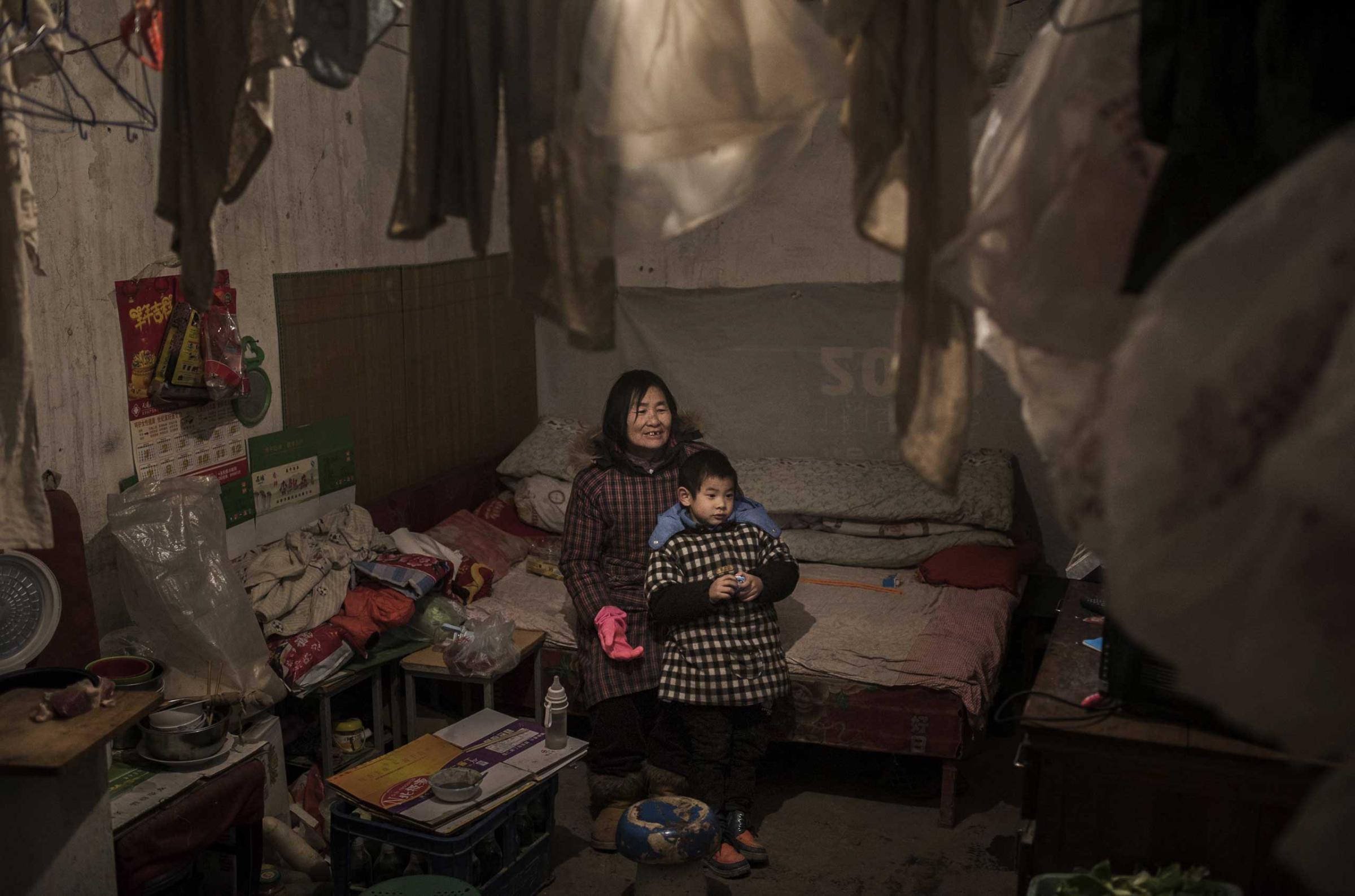 A laborer watches television with her grandson in the Dong Xiao Kou scrap village on Dec. 11, 2014 in Beijing.