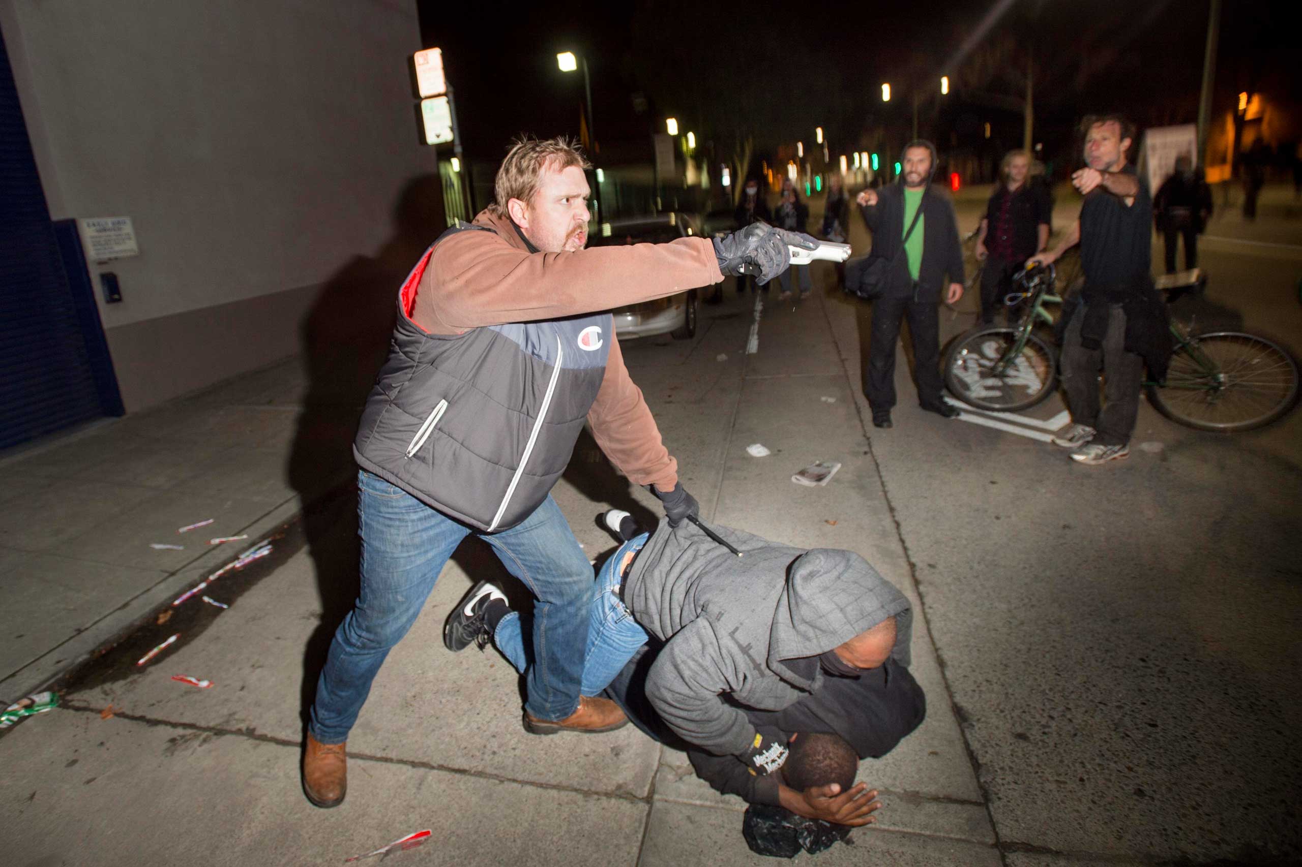 An undercover police officer aims his gun at protesters after some in the crowd attacked him and his partner in Oakland, Calif. on Dec. 10, 2014. (Noah Berger—Reuters)