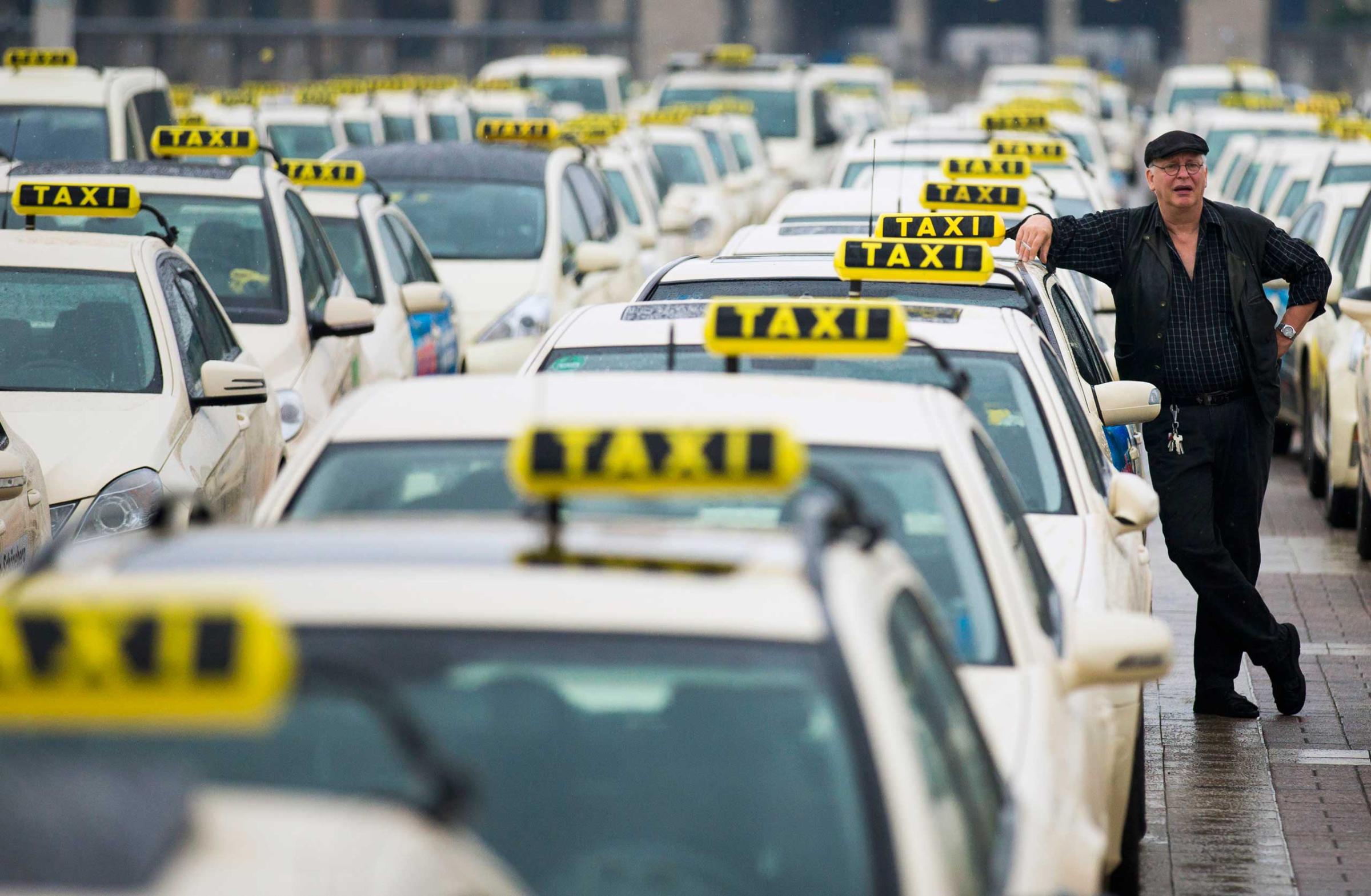 A taxi driver listens to speeches by his colleagues, during an Europe-wide protest of licensed taxi drivers against taxi hailing apps that are feared to flush unregulated private drivers into the market, in front of the Olympic stadium in Berlin on June 11, 2014.