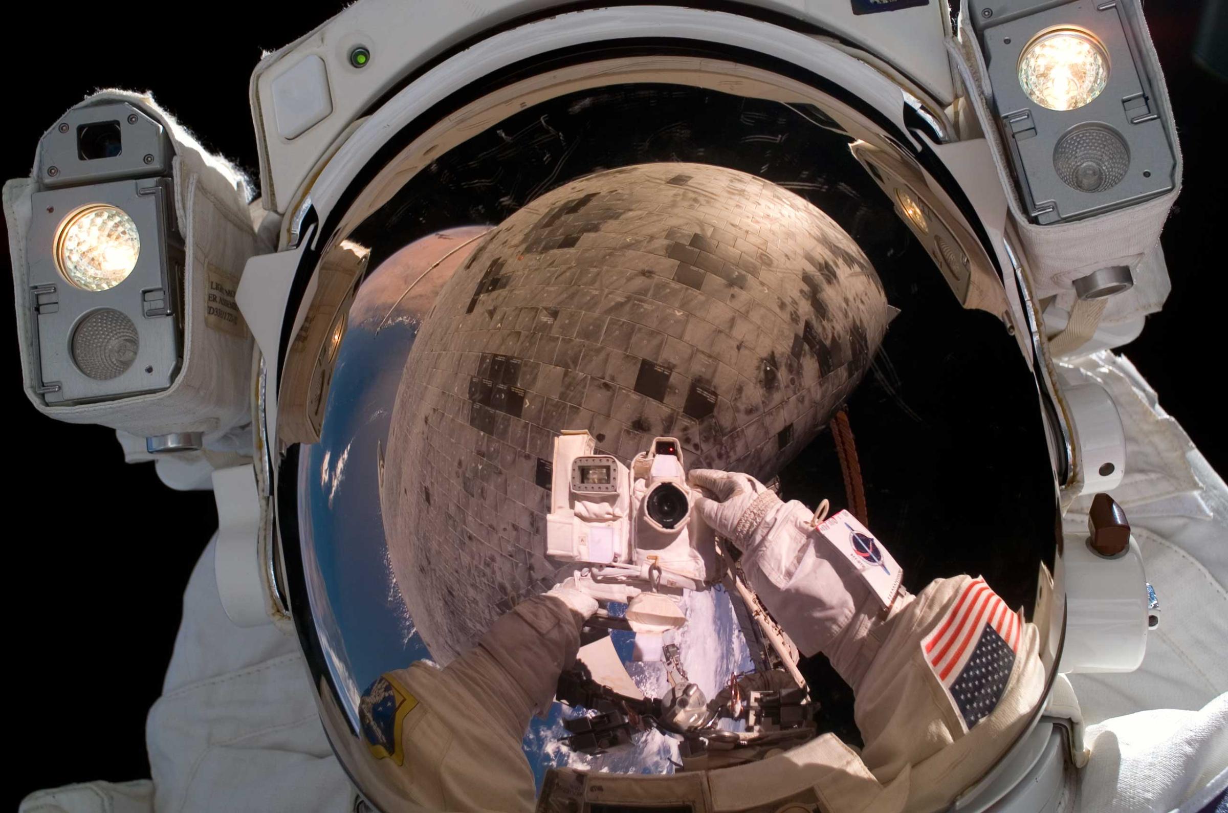 Astronaut Stephen K. Robinson, STS-114 mission specialist, used a digital camera to expose a photo of his helmet visor during the third Extravehicular Activity EVA of the mission. Also visible in the reflection are thermal protection tiles on Space Shuttle Discovery's under Aug. 3, 2005.