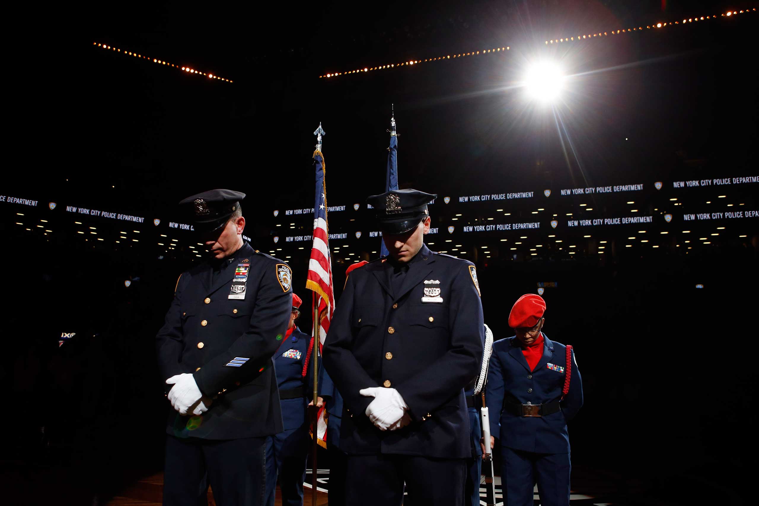 New York Police Department officers Mark Cava, left, and Jason Muller participate in a moment of silence for two slain NYPD officers before an NBA basketball game between the Brooklyn Nets and the Detroit Pistons on Dec. 21, 2014, in New York City. (Jason DeCrow—AP)