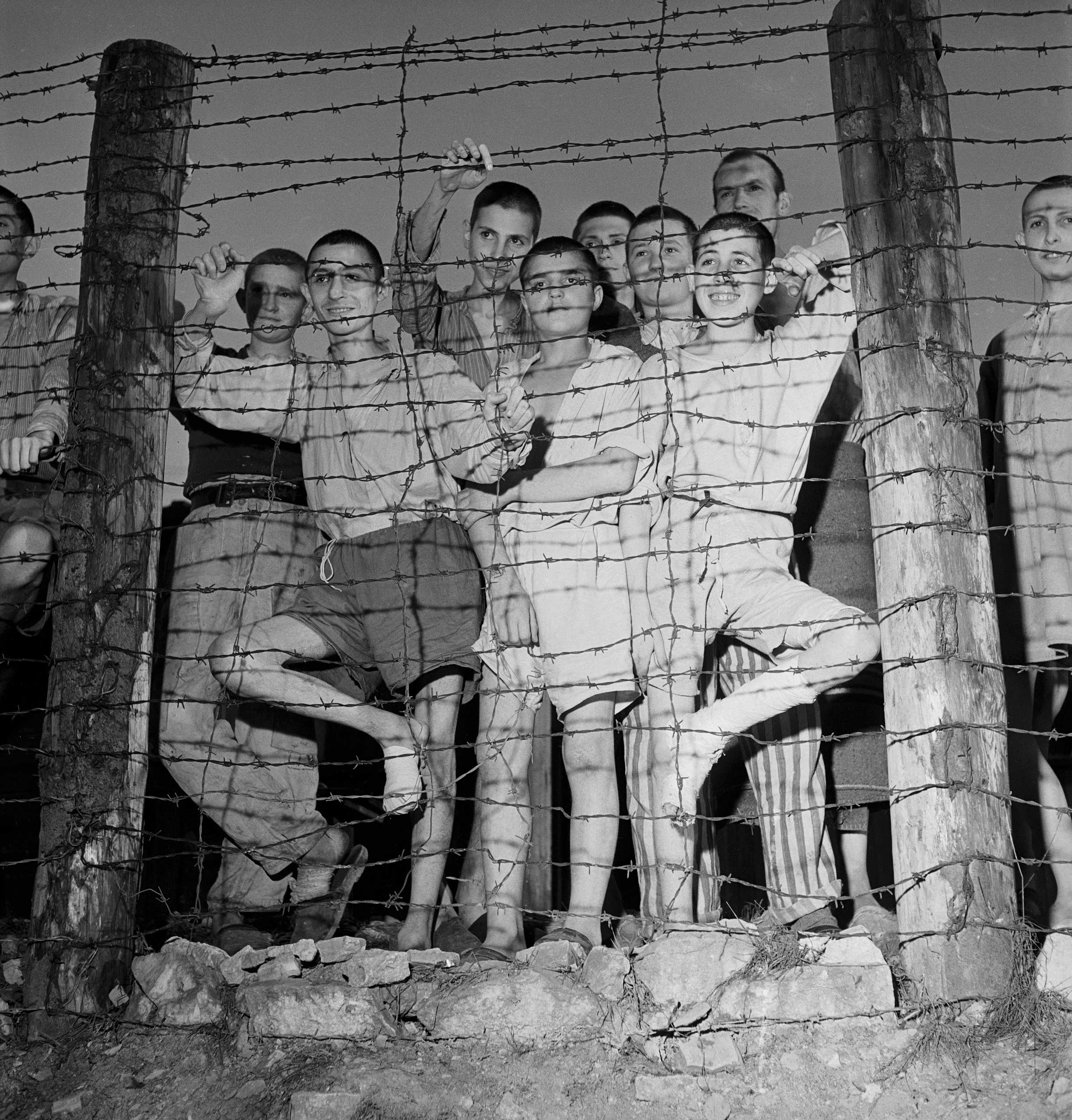 Not published in LIFE. Prisoners at Buchenwald gaze from behind barbed wire during the camp's liberation by American forces, April 1945.