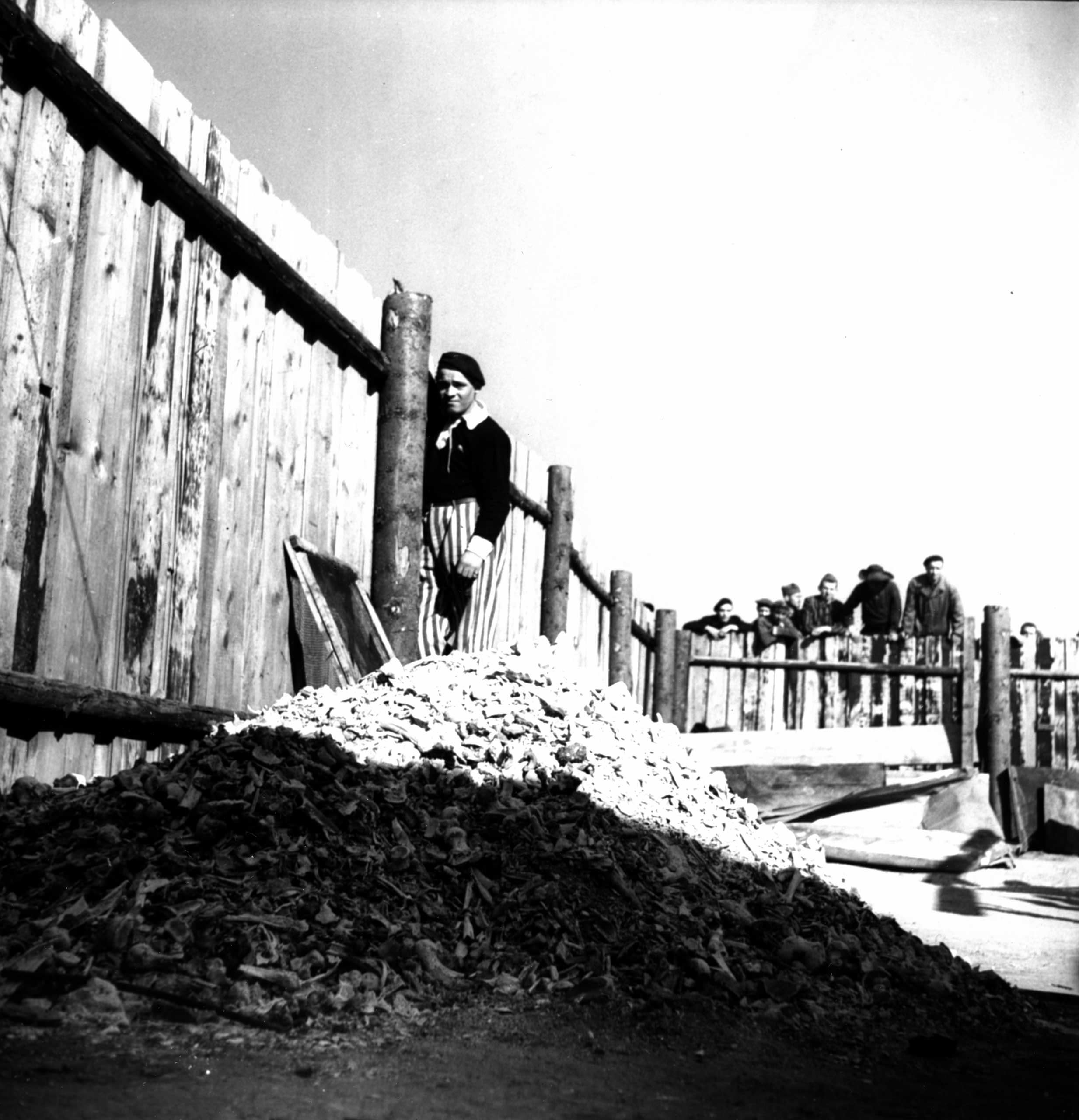 Not published in LIFE. A newly liberated prisoner stands beside a pile of human ashes and bones, Buchenwald, April 1945.