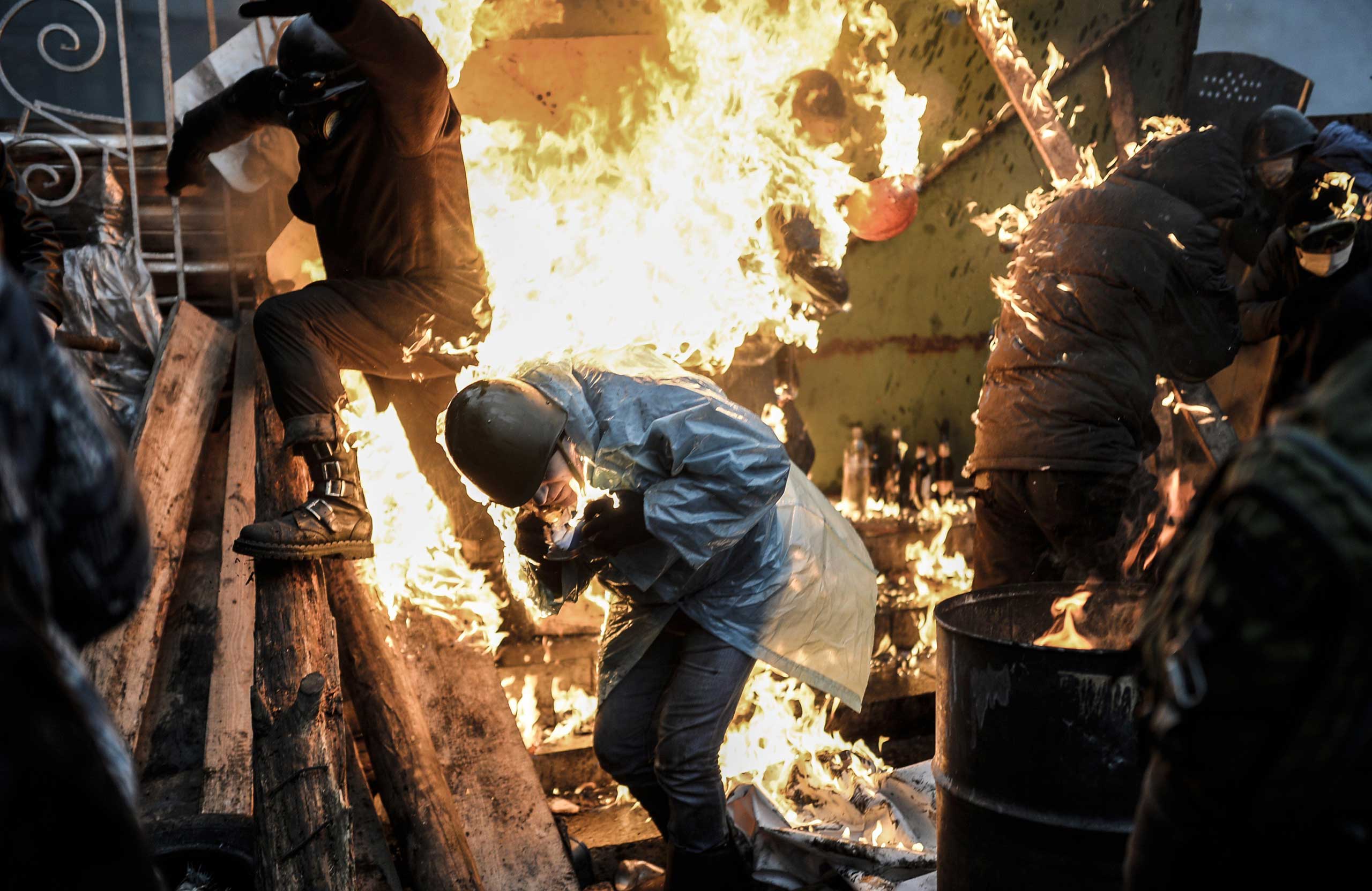Protesters burn as they stand behind burning barricades during clashes with police on February 20, 2014 in Kiev, Ukraine. (Bulent Kilic—AFP/Getty Images)