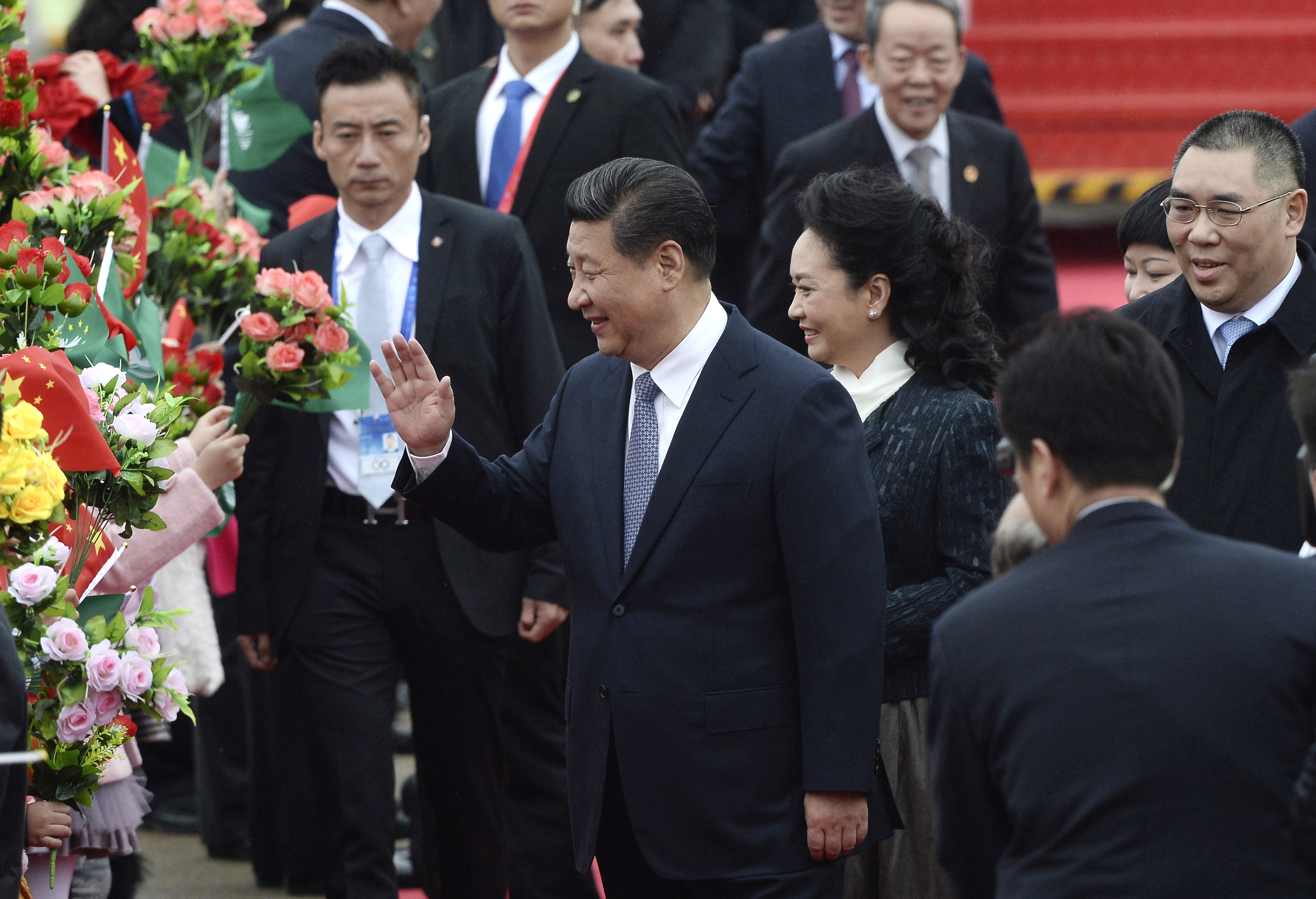 In this photo provided by China's Xinhua News Agency, Chinese President Xi Jinping, center, and his wife Peng Liyuan, center right,  wave as they arrive at the international airport in Macau on Dec. 19, 2014 (Cheong Kam Ka—AP)