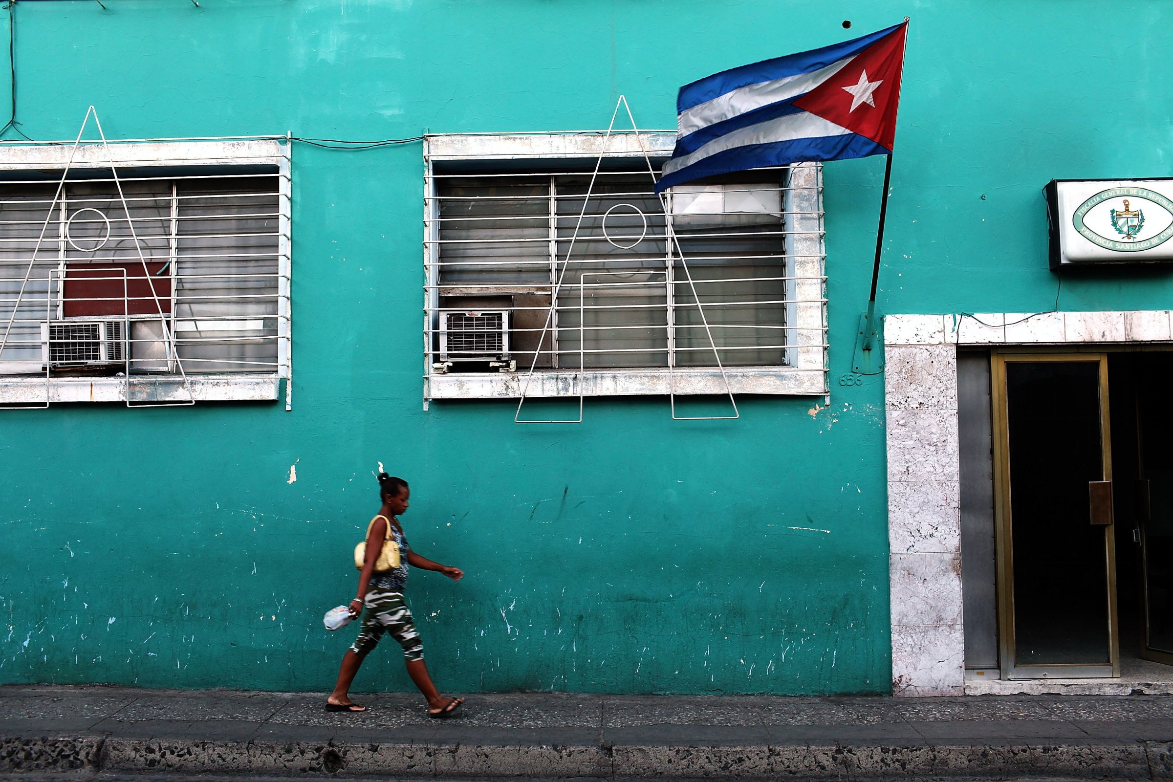 A woman walks under a Cuban flag on March 22, 2012 in Santiago de Cuba, Cuba.