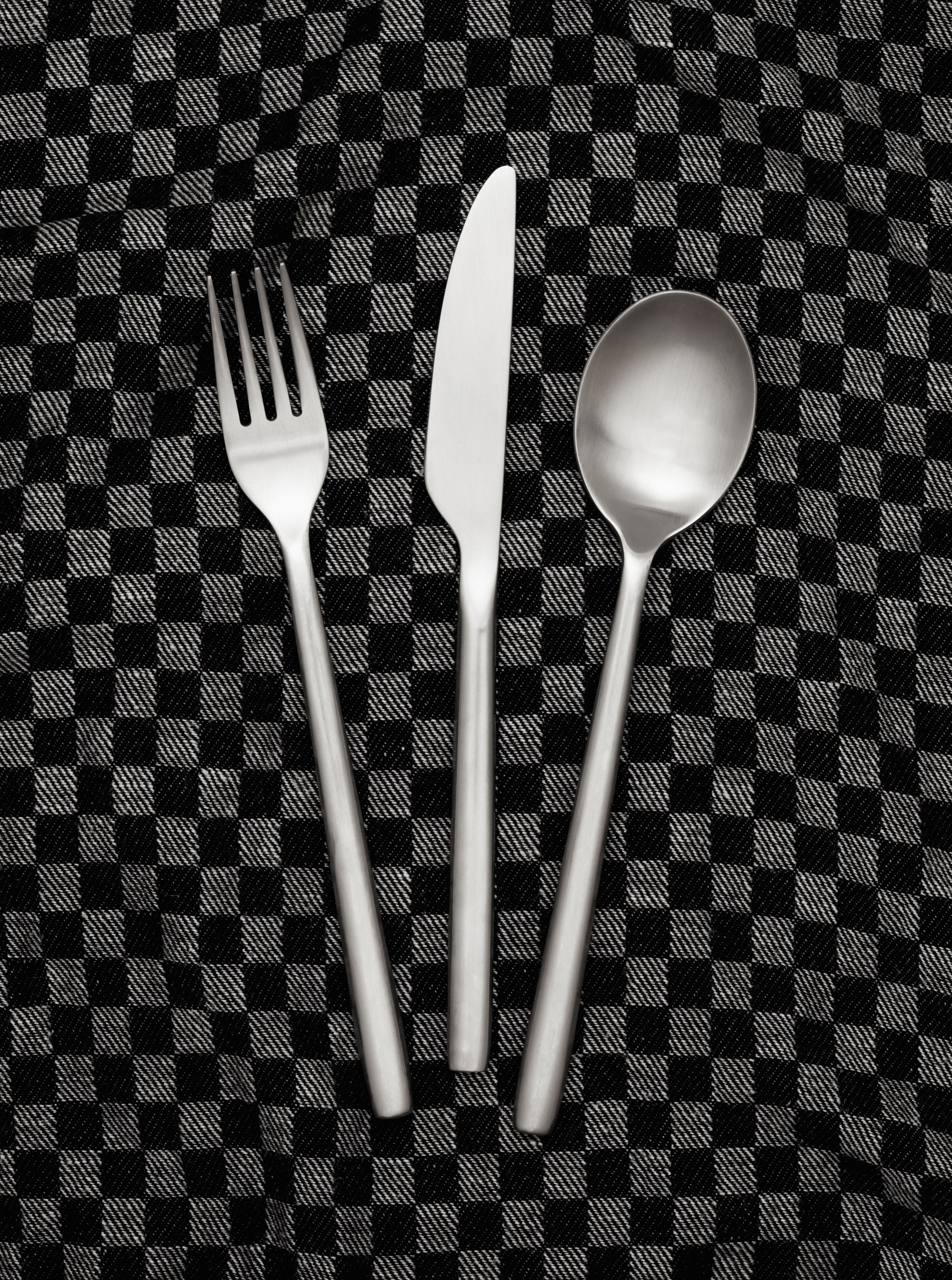 Fork, knife and spoon on dishcloth
