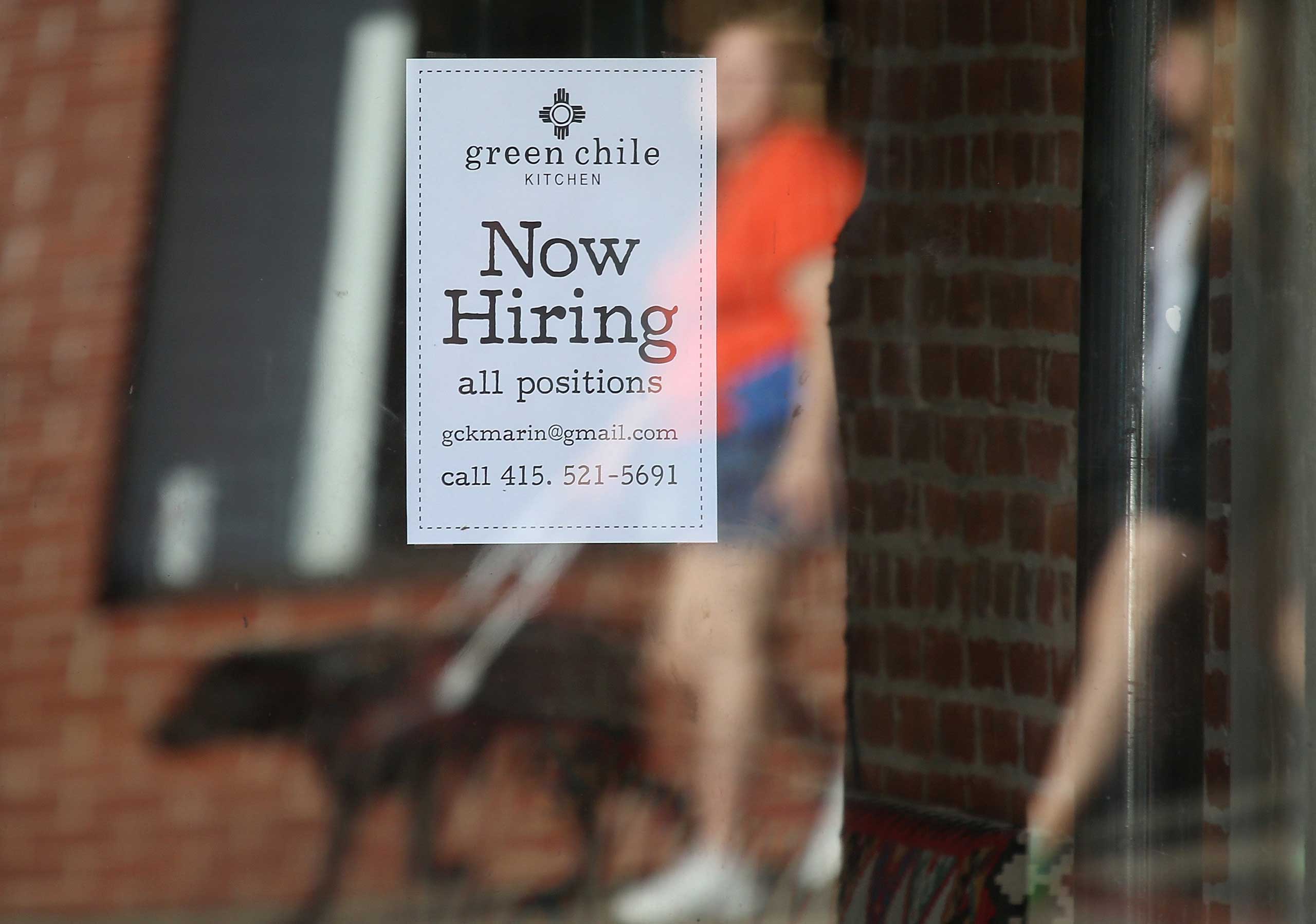 Pedestrians walk by a now hiring sign posted in the window of a business on Nov. 7, 2014 in San Rafael, Calif. (Justin Sullivan—Getty Images)