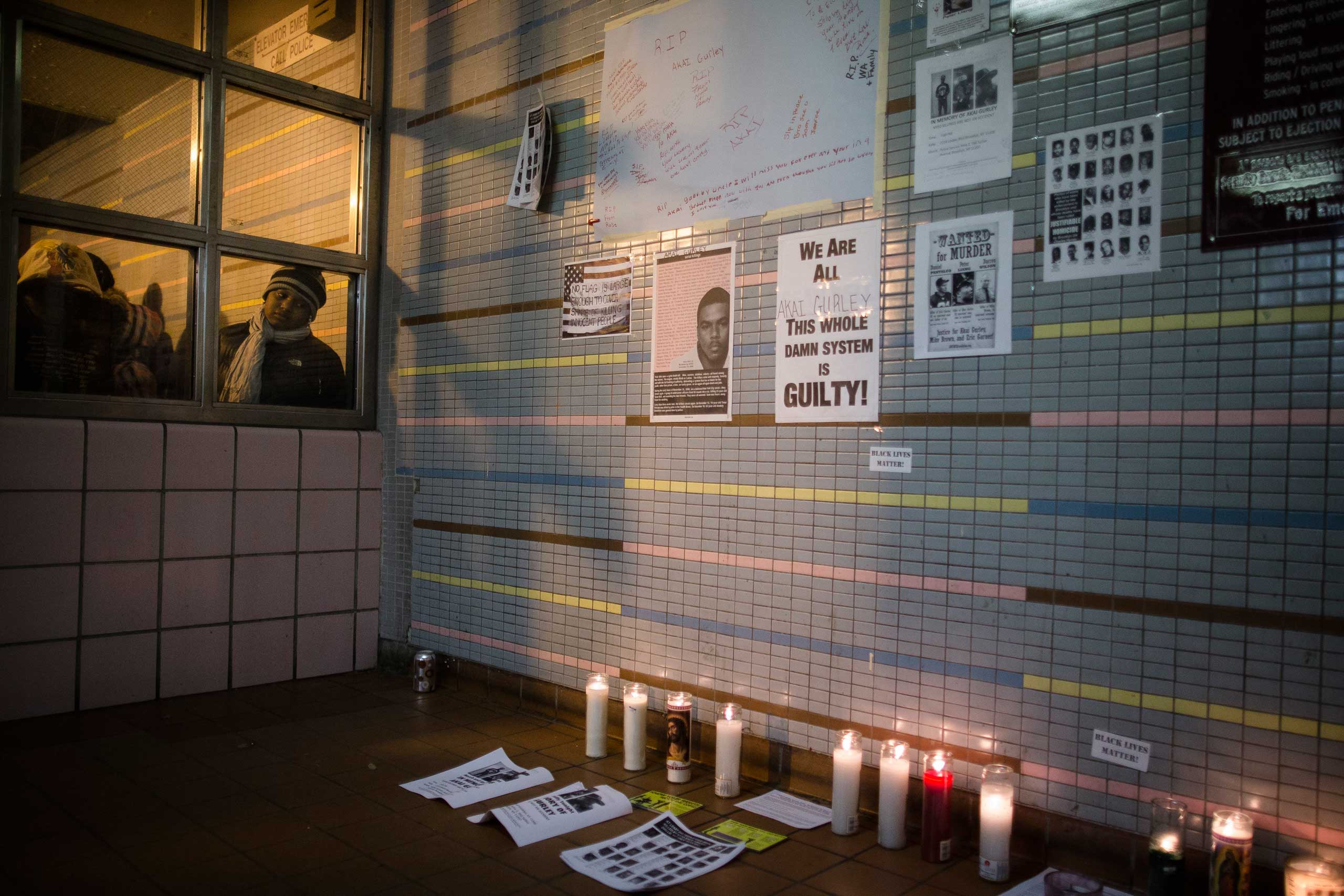A demonstrator looks on a memorial to Akai Gurley who was shot to death by rookie NYPD officer Peter Liang at the Louis Pink Houses public housing complex, Nov. 22, 2014, in the Brooklyn borough of New York. (John Minchillo&mdash;AP)