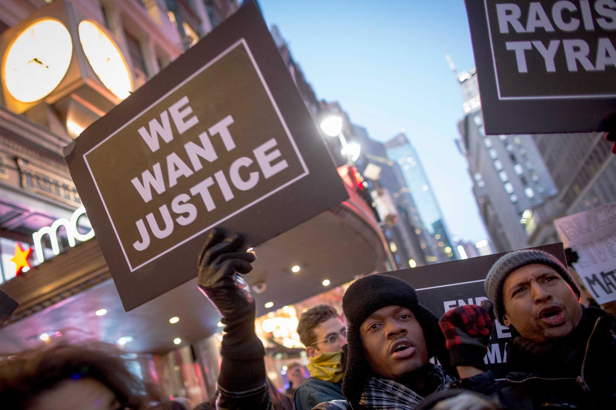 A protester holds up a sign while demonstrating outside of Macy's in Herald Square during the Black Friday shopping day in New York