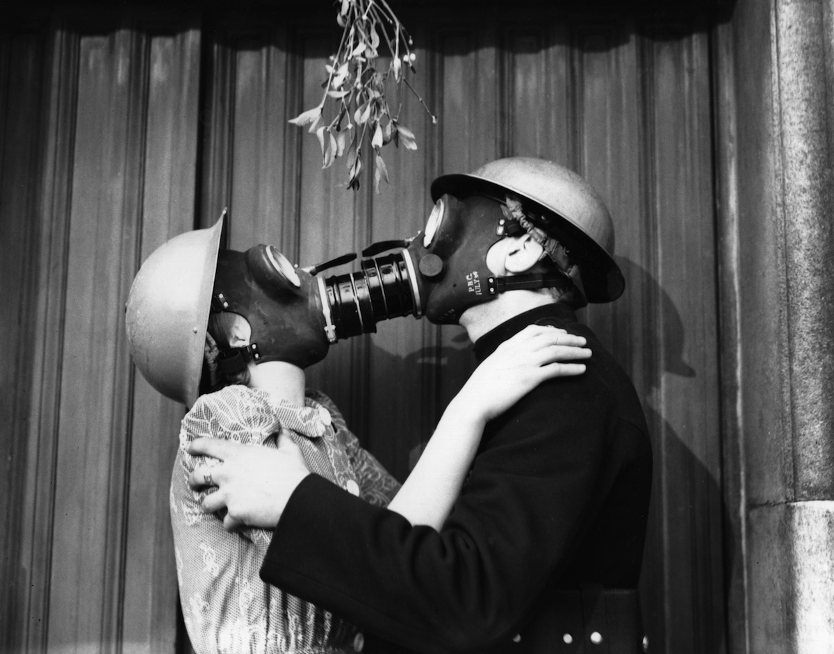 A couple kissing under the mistletoe, wearing gas masks, in 1940 (Fox Photos / Getty Images)
