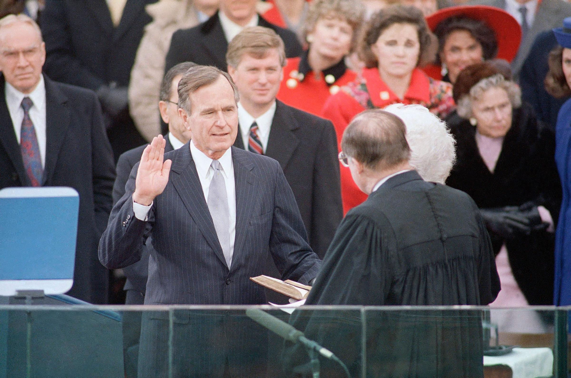 President George H. W. Bush raises his hand as he takes the oath of office as President of the United States outside the Capitol on Jan. 20, 1989, Washington, D.C.