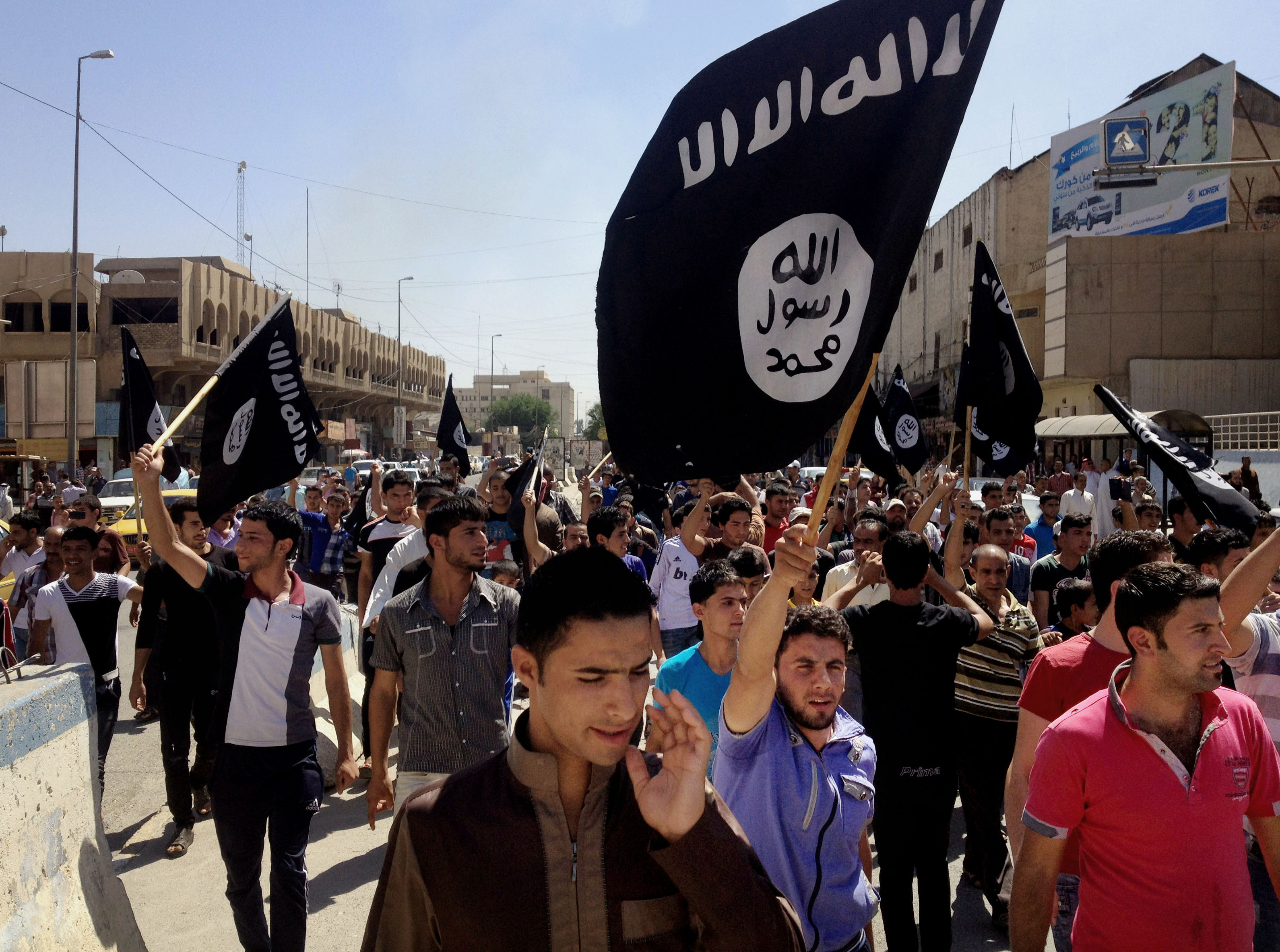 In this June 16, 2014, file photo, supporters of the Islamic State of Iraq and Greater Syria chant slogans as they carry the group's flags in Mosul, Iraq (STR—AP)