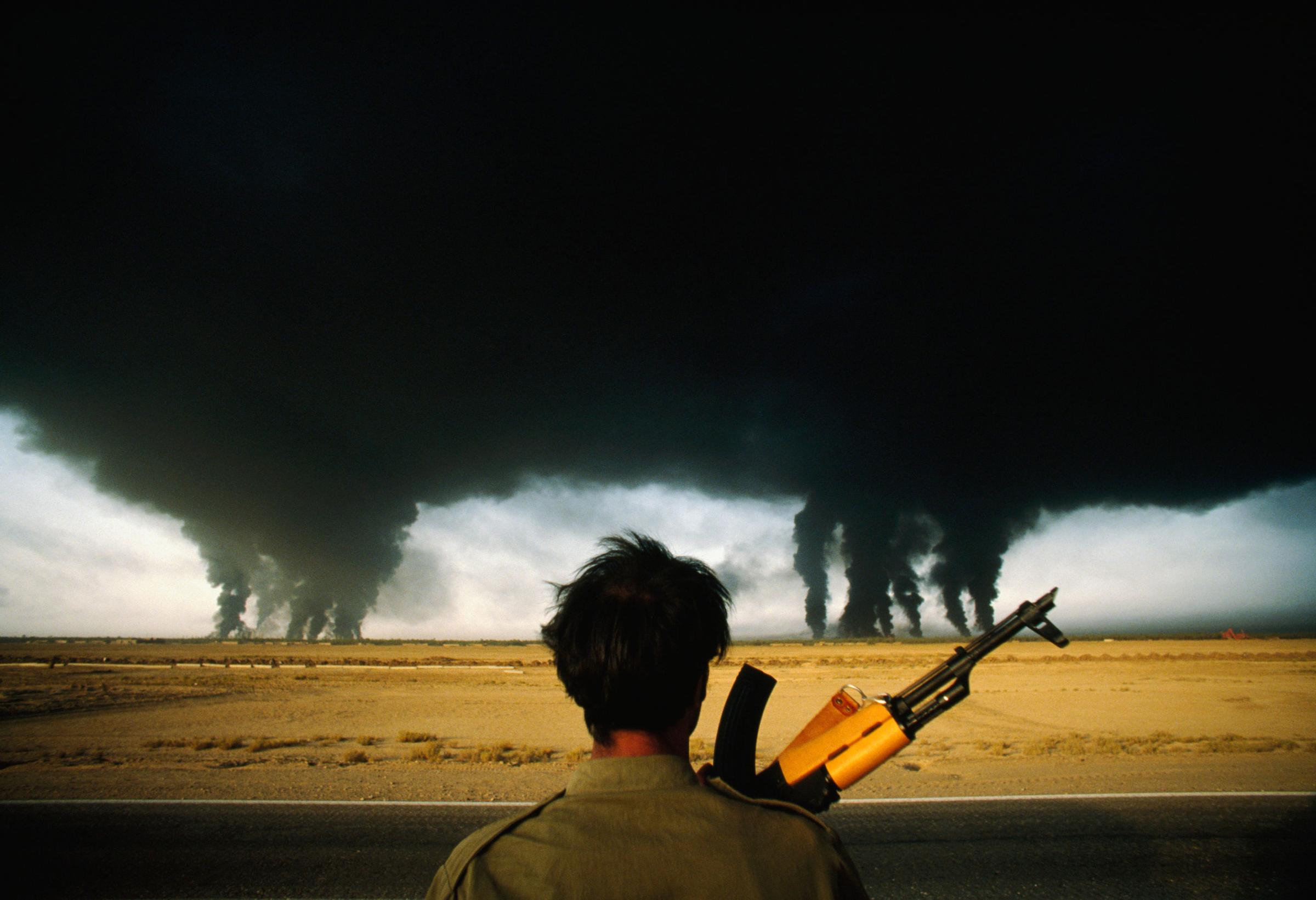 An Iranian soldier watches as smoke billows from multiple burning oil refineries in Abadan, Iran on Sept. 27, 1980.
