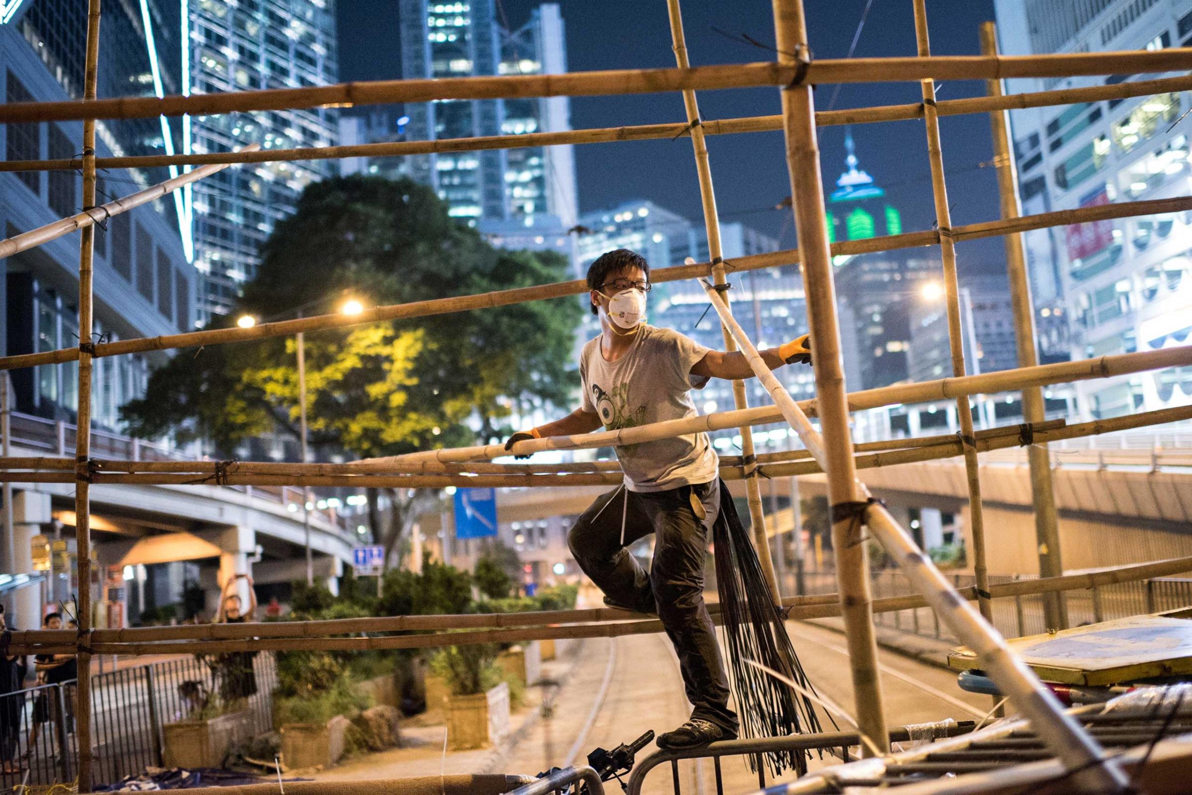A pro-democracy protester uses bamboo to strengthen a barricade blocking a major road in Hong Kong on Oct. 13, 2014.