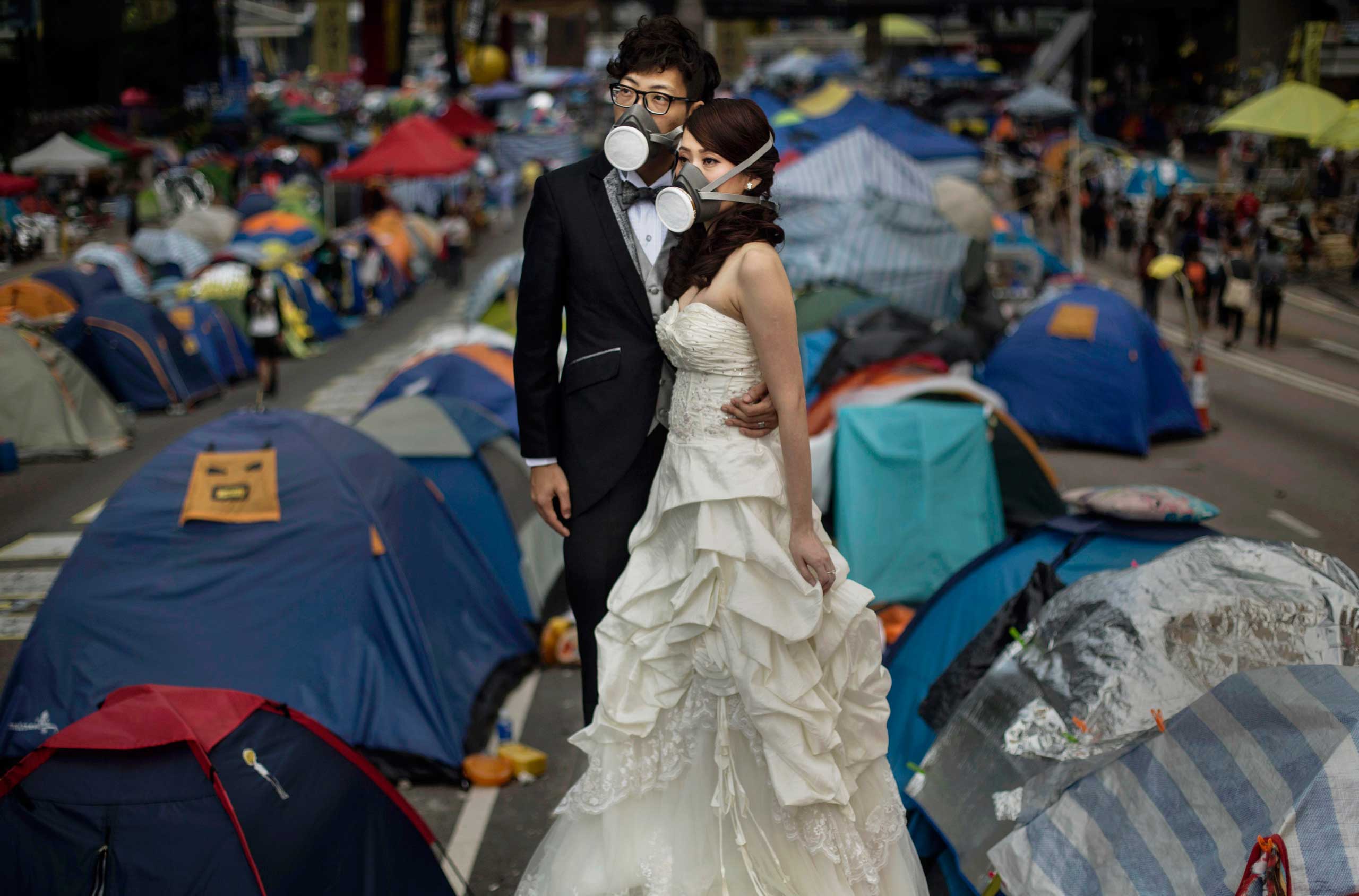 A young Hong Kong couple who did not give their names wear gas masks as they pose for a wedding photographer prior to their marriage next to the tents used by pro-deocracy demonstrators at the Admiralty protest site on Nov. 14, 2014 in Hong Kong.