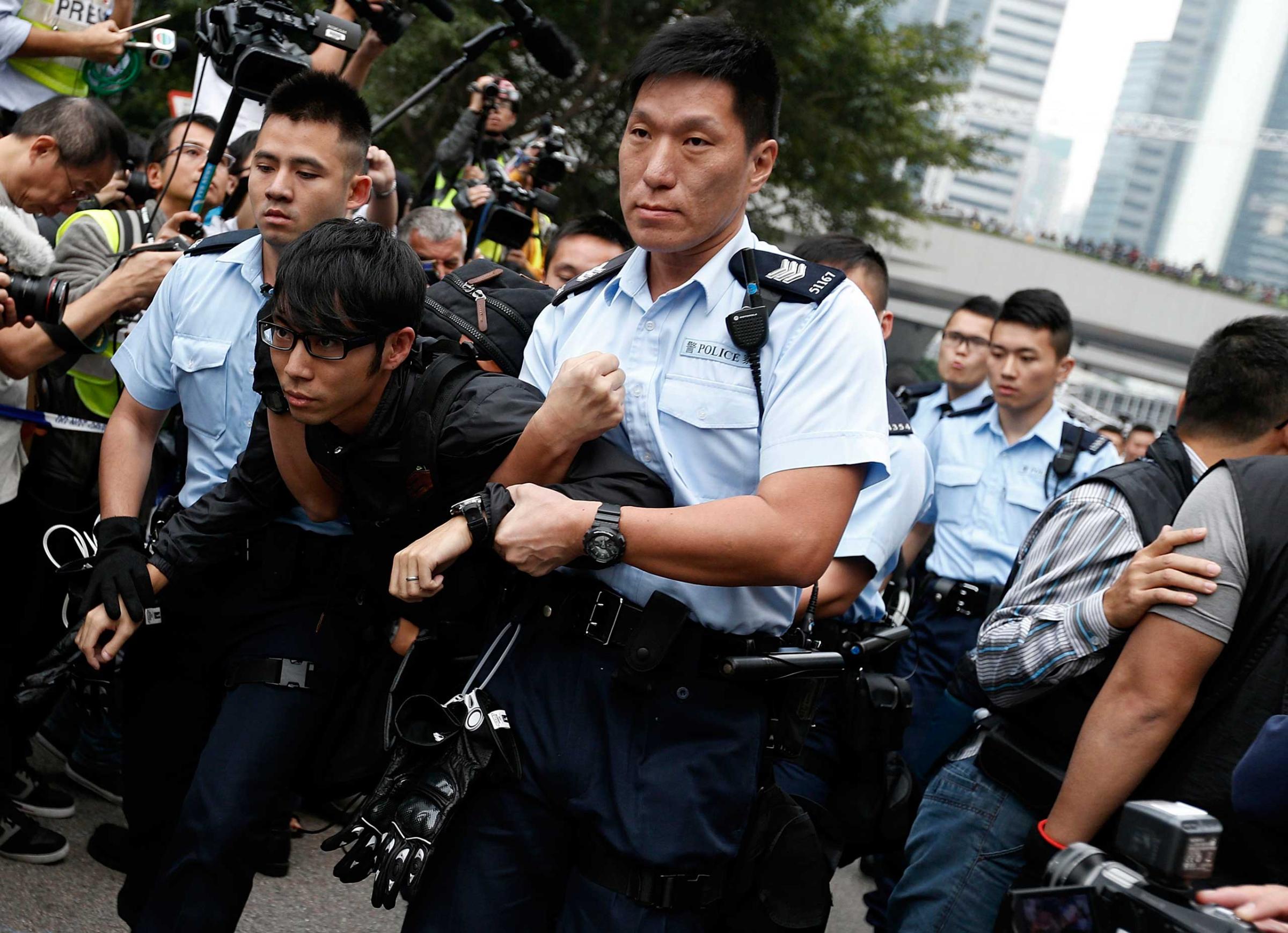A demonstrator is taken away by policemen, at an area previously blocked by pro-democracy supporters, outside the government headquarters in Hong Kong, Dec. 11, 2014.