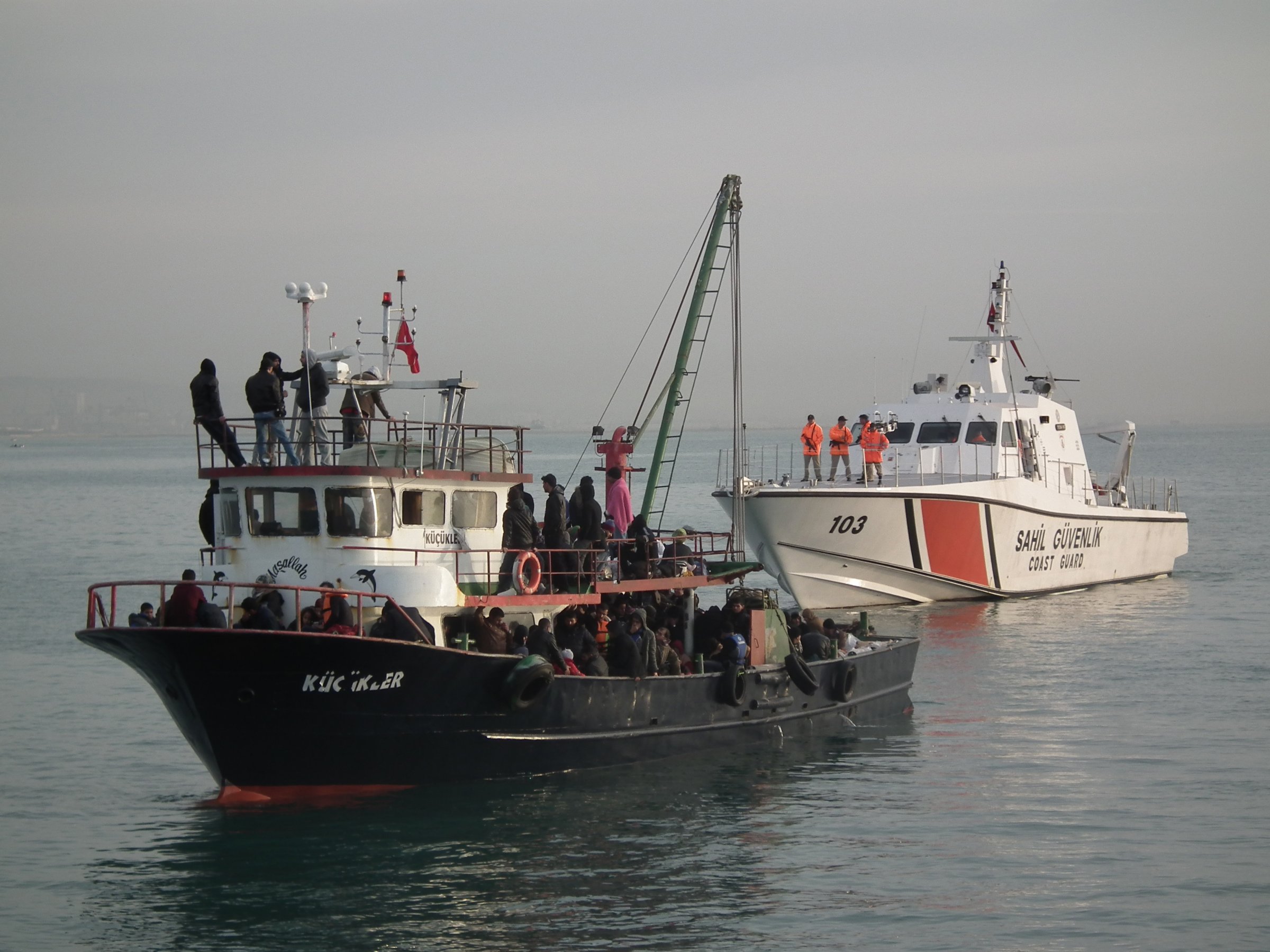 MERSIN, TURKEY - DECEMBER 06:  Illegal immigrants are escorted by the officers of Turkey's Coast Guard Mediterranean Region Command as they arrive in Mersin, Turkey on December 06, 2014. Some 361 illegal migrants and six organizers of the illegal crossing were captured while trying to illegally reach Europe on fishing boats. (Photo by Turkish Coast Guard Command/Anadolu Agency/Getty Images)