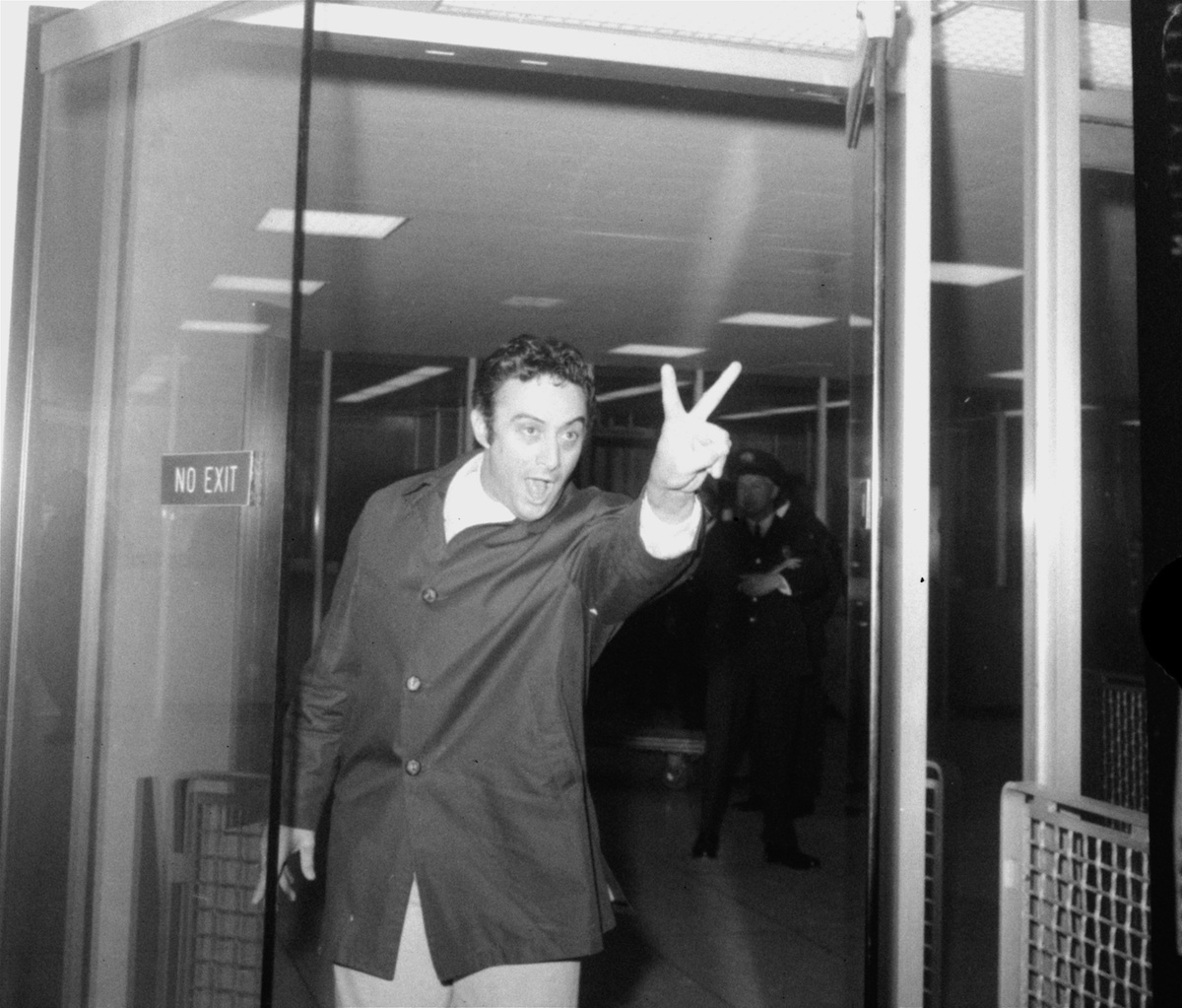Lenny Bruce, refused entry to Britain earlier in the day  "in the public interest," makes a V-sign as he leaves U.S. customs office after returning to New York's Idlewild Airport on Apr. 8, 1963. (John Lindsay—AP Photo)