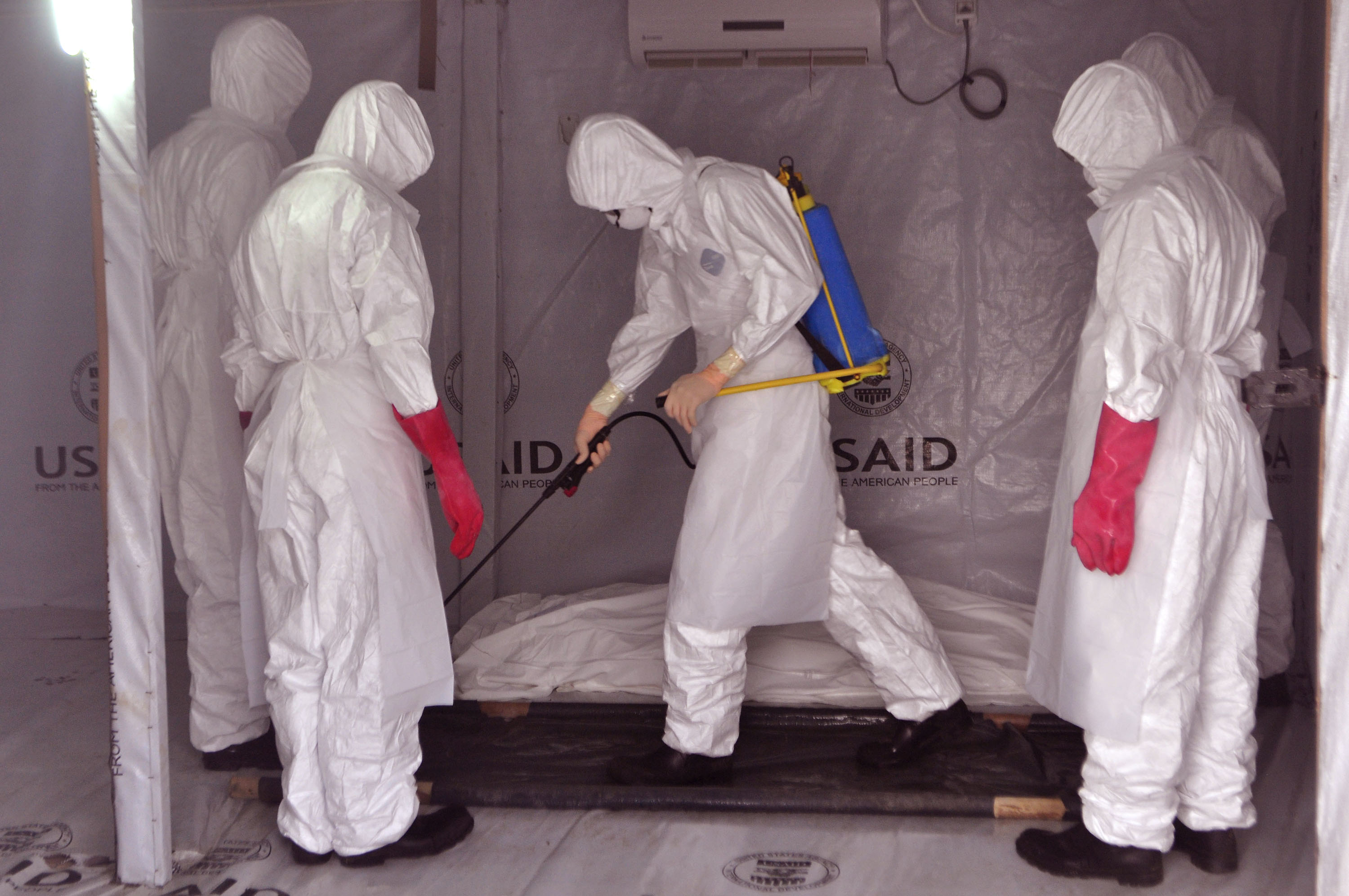 Health workers wearing Ebola protective gear spray the shrouded body of a suspected Ebola victim with disinfectant at an Ebola treatment center at Tubmanburg, on the outskirts of  Monrovia, Liberia, on Nov. 28, 2014 (Abbas Dulleh—AP)
