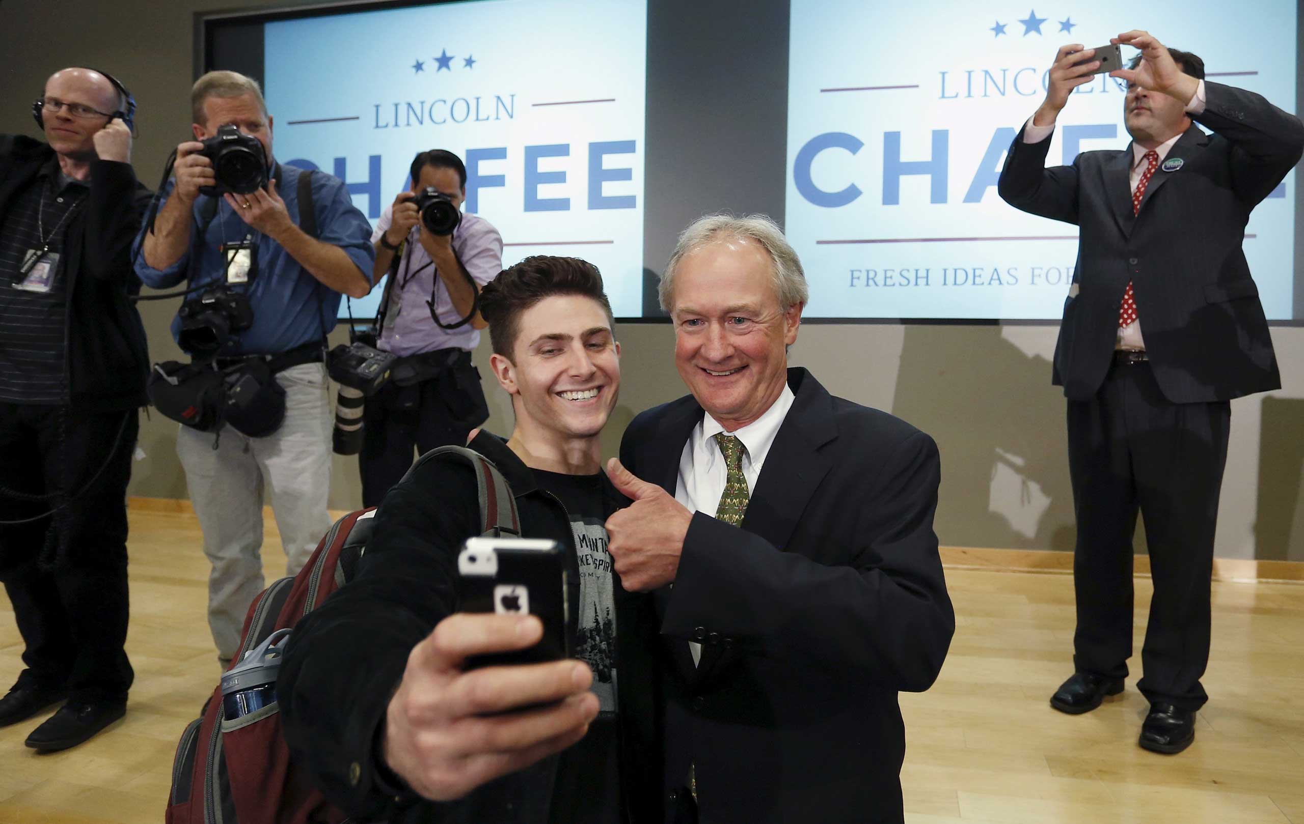 Former Rhode Island Governor Chafee poses for a selfie with a student after announcing he will seek the Democratic nomination to be U.S. president during an address to the GMU School of Policy, Government, and International Affairs in Arlington