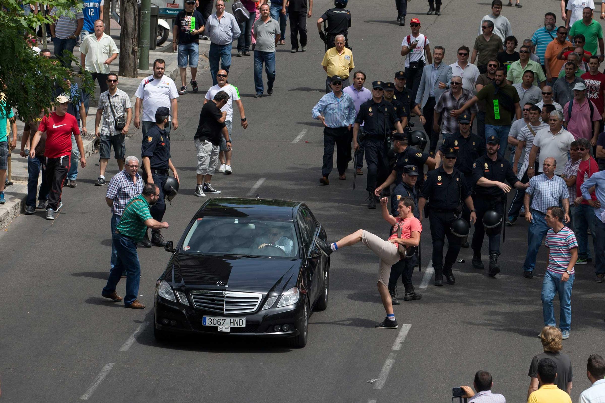 A demonstrator kicks a car, suspected of being a private taxi during a 24 hour taxi strike and protest in Madrid on June 11, 2014.