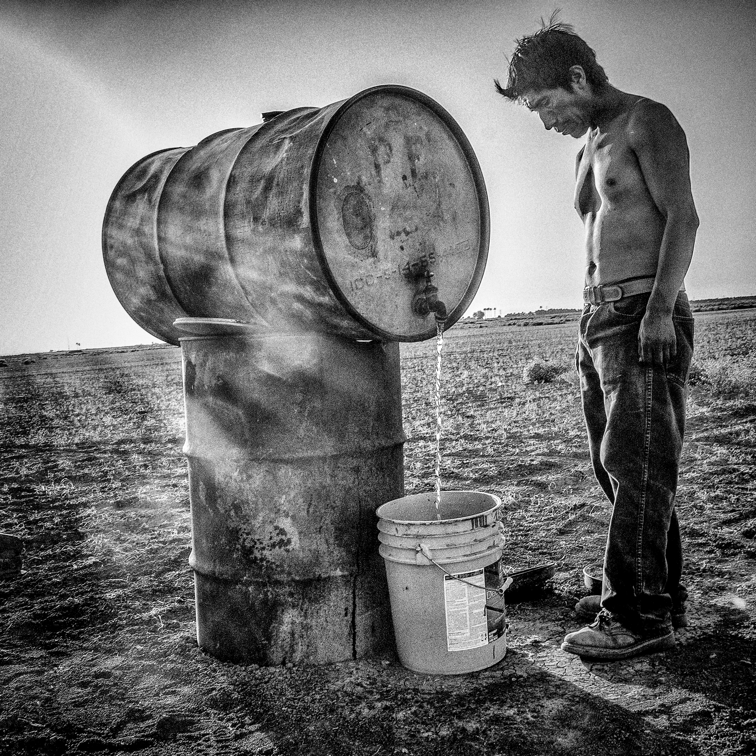 A shepherd's camp in a dry wheat field.  Mendota, CA.  His water for drinking, bathing and cooking comes from this 55-gallon drum.