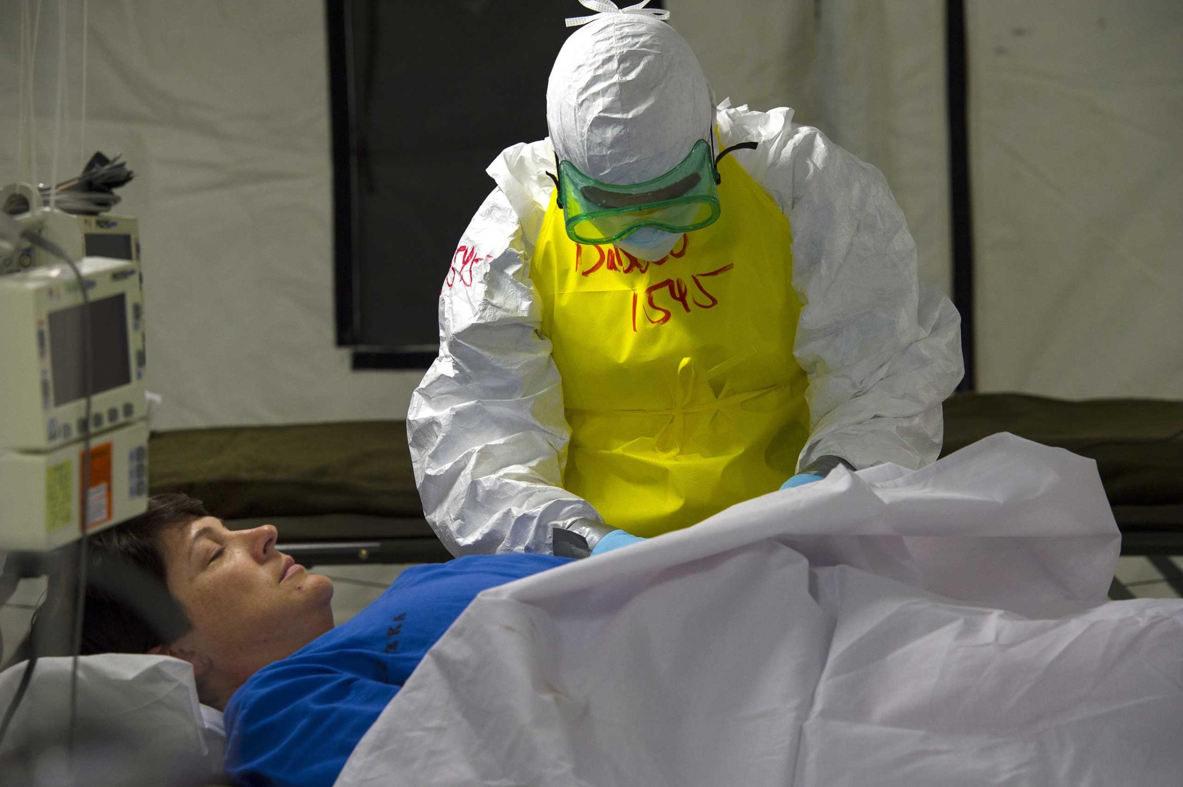 Medical staff members LT. Junior Grade Lauren Ryszka acts as a patient in bed while LT. Junior Grade Victoria D'Addeo simulate treating her as an Ebola patient inside the Monrovia Medical Unit on Nov. 4, in Monrovia, Liberia.