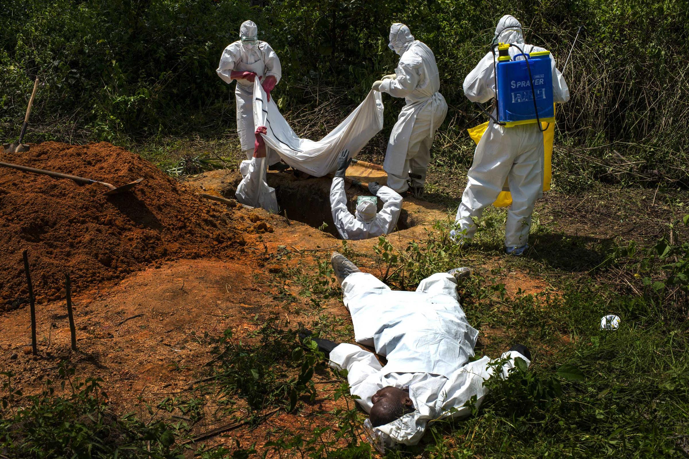 Alexander Morris lays flat on his back after fainted due to the extreme heat inside a protective suit while the Lofa County health department team buried his sister, on Nov. 7, 2014 in Voinjama, Liberia.