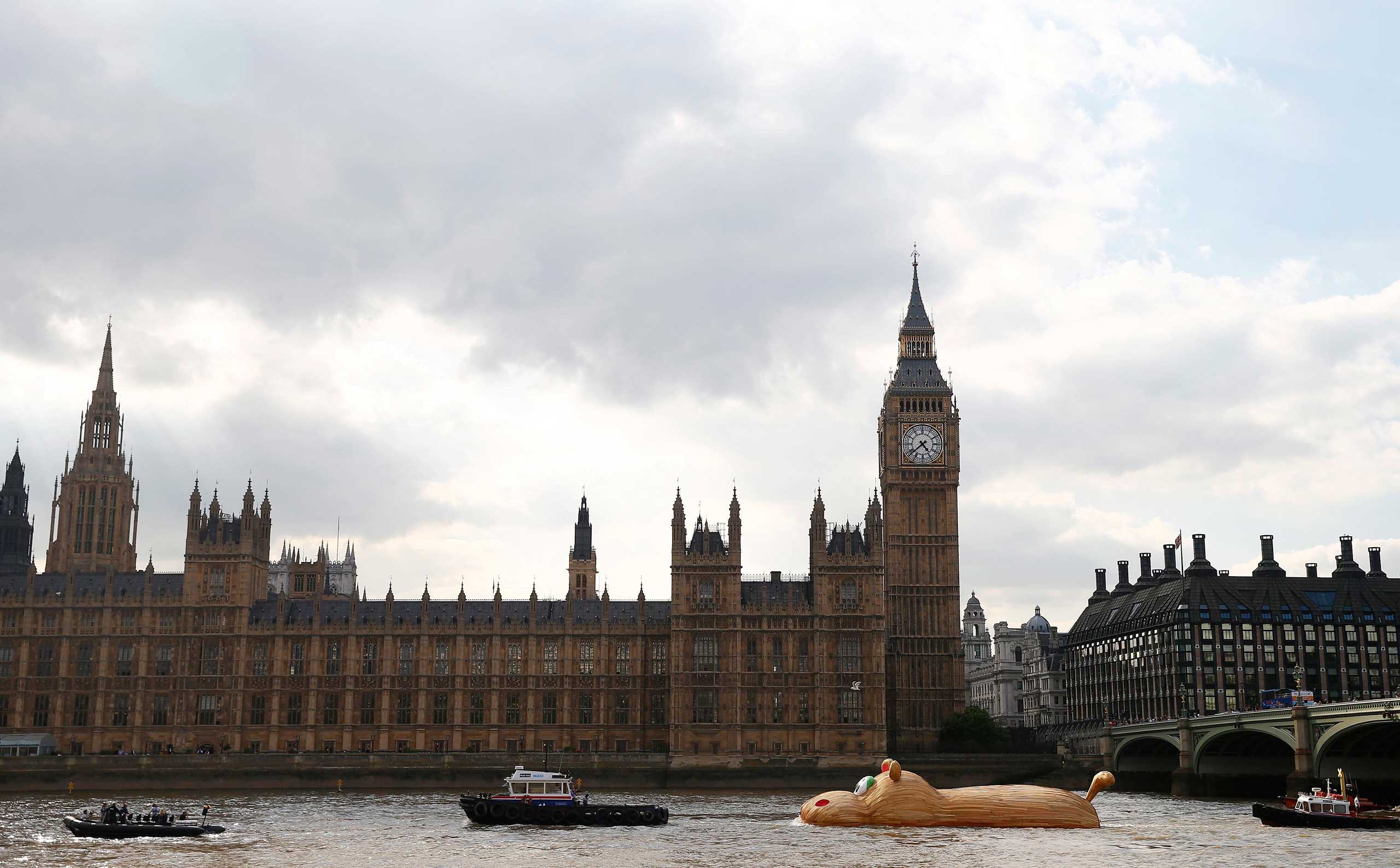 A sculpture of a giant hippopotamus built by artist Florentjin Hofman is towed up the Thames past the Houses of Parliament in central London, Sept. 2, 2014.