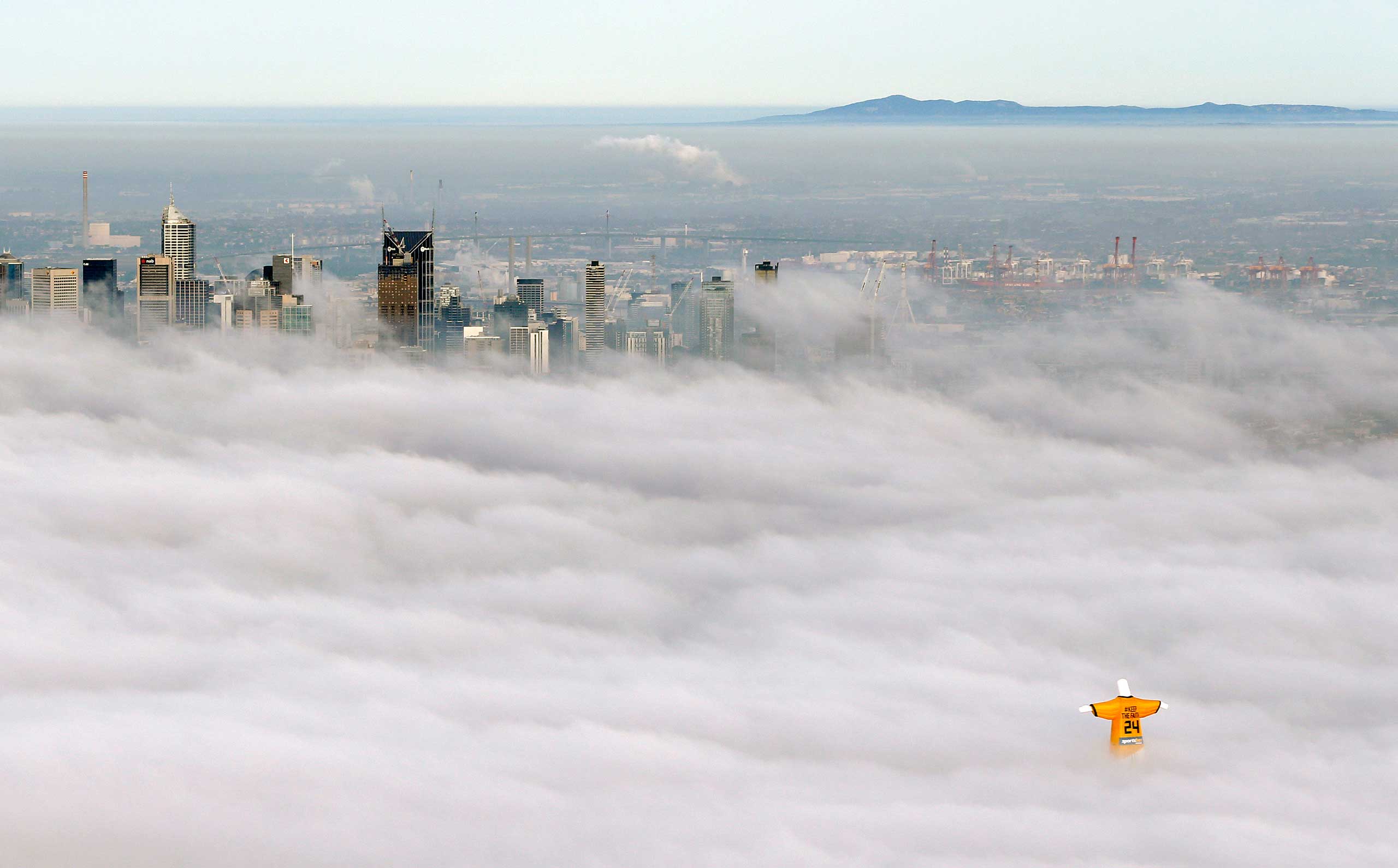 A hot air balloon in the likeness of Brazil's Christ the Redeemer statue wearing the colors of Australia's soccer team, floats through clouds over the Melbourne skyline, June 10, 2014.