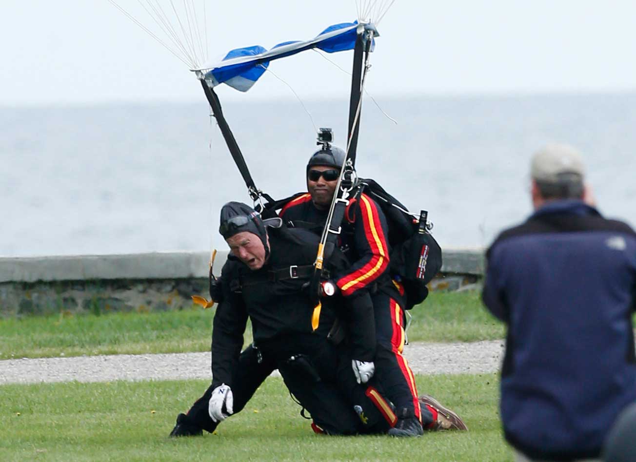 Former President George H.W. Bush, left, strapped to Sgt. 1st Class Mike Elliott, a retired member of the Army's Golden Knights parachute team, land on the lawn at St. Anne's Episcopal Church after making a tandem parachute jump near Bush's summer home in Kennebunkport, Maine, Thursday, June 12, 2014. (Robert F. Bukaty—;AP)