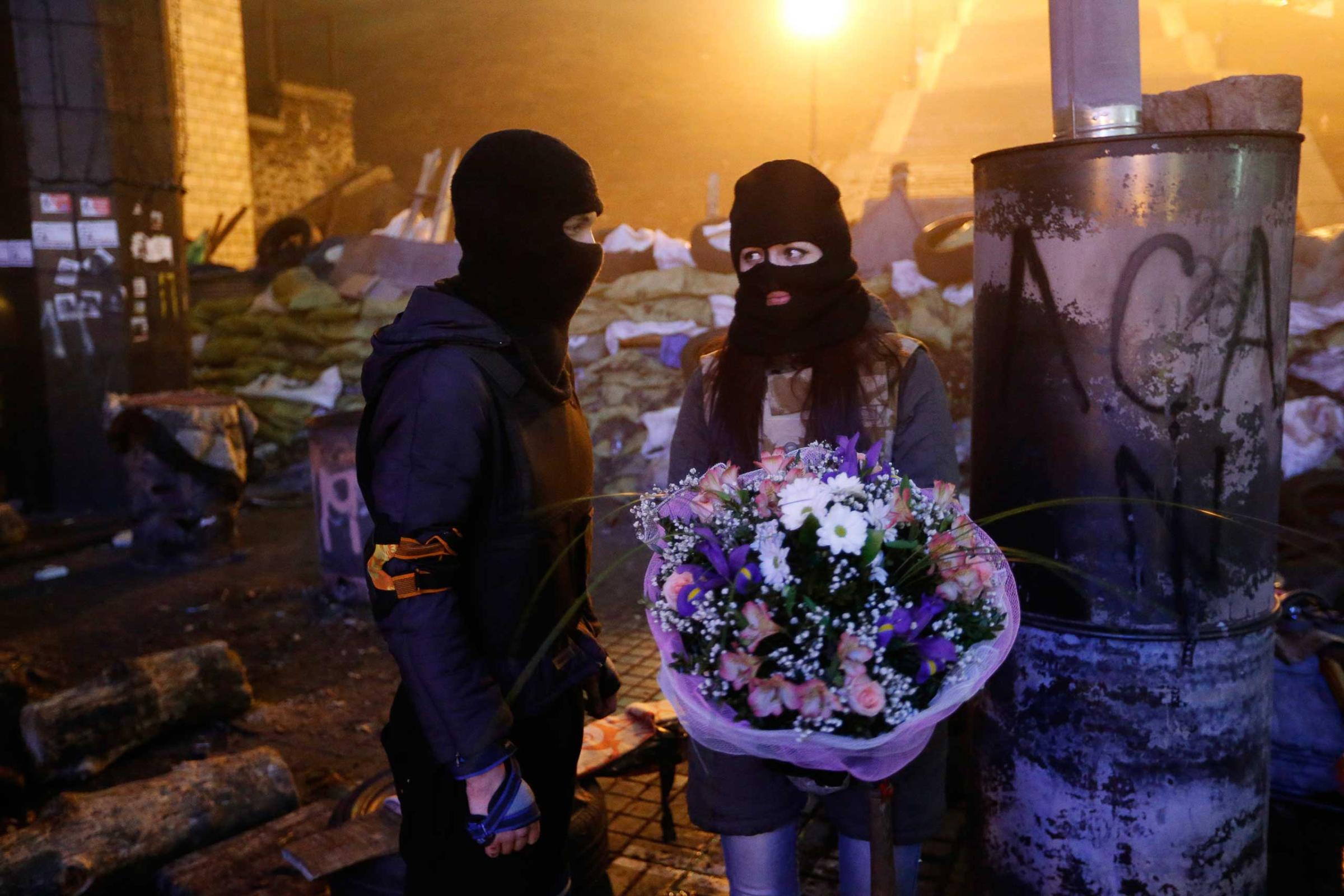 An activist from the "Right Sector" anti-government protest group presents flowers to his girlfriend in front of fellow activists near the site of previous clashes with riot police in Kiev
