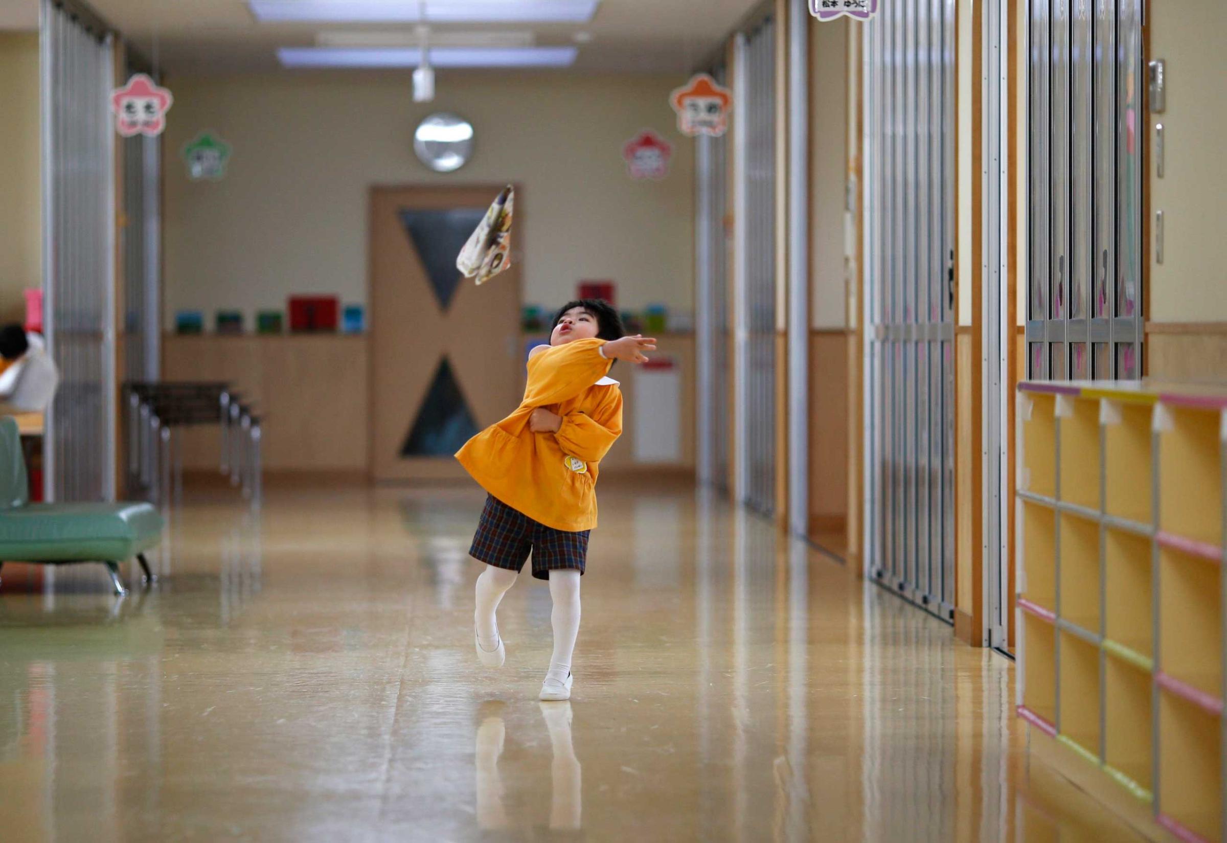 A boy plays with a paper plane at the corridor of the Emporium kindergarten in Koriyama