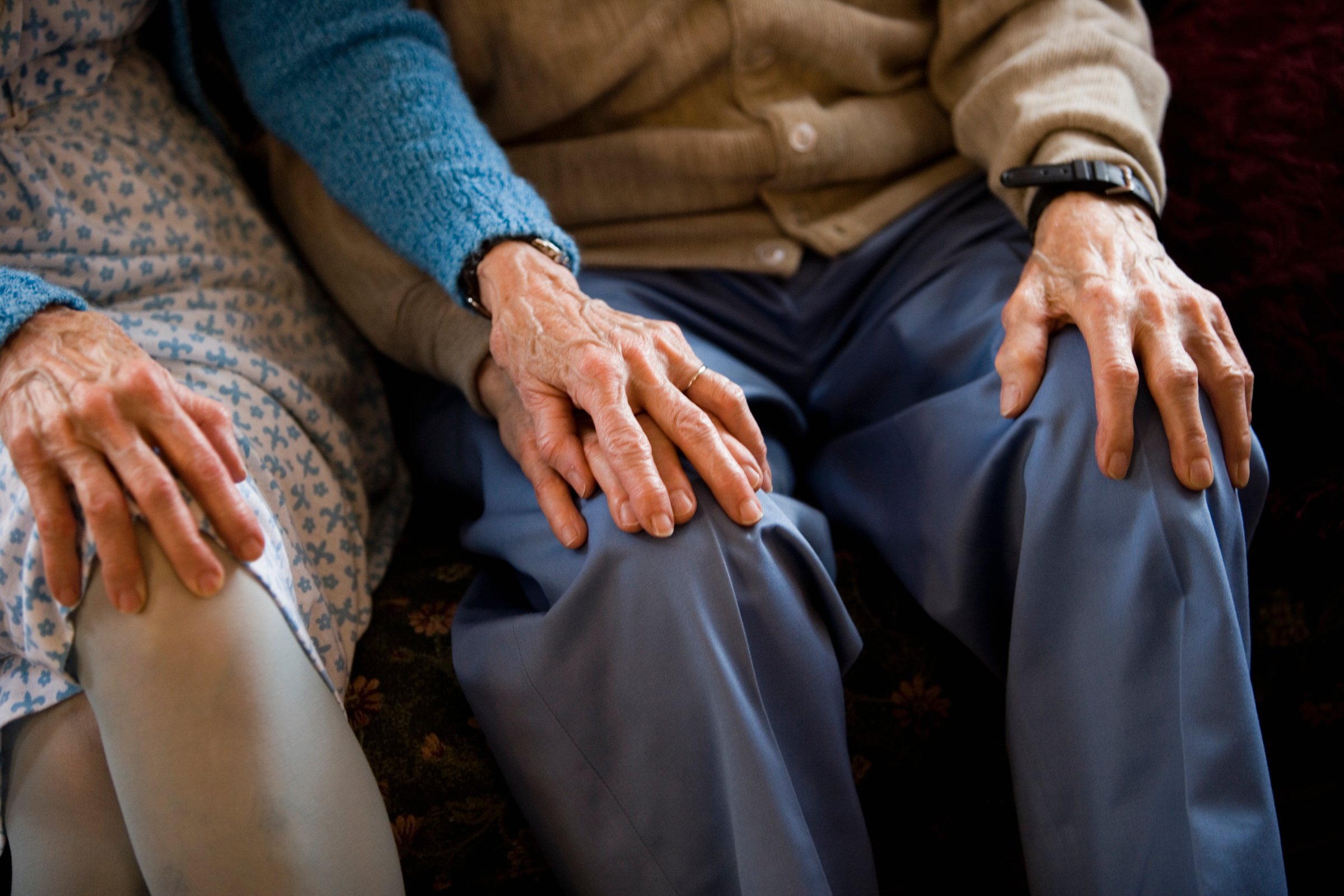 Close-up of senior couple holding hands while sitting