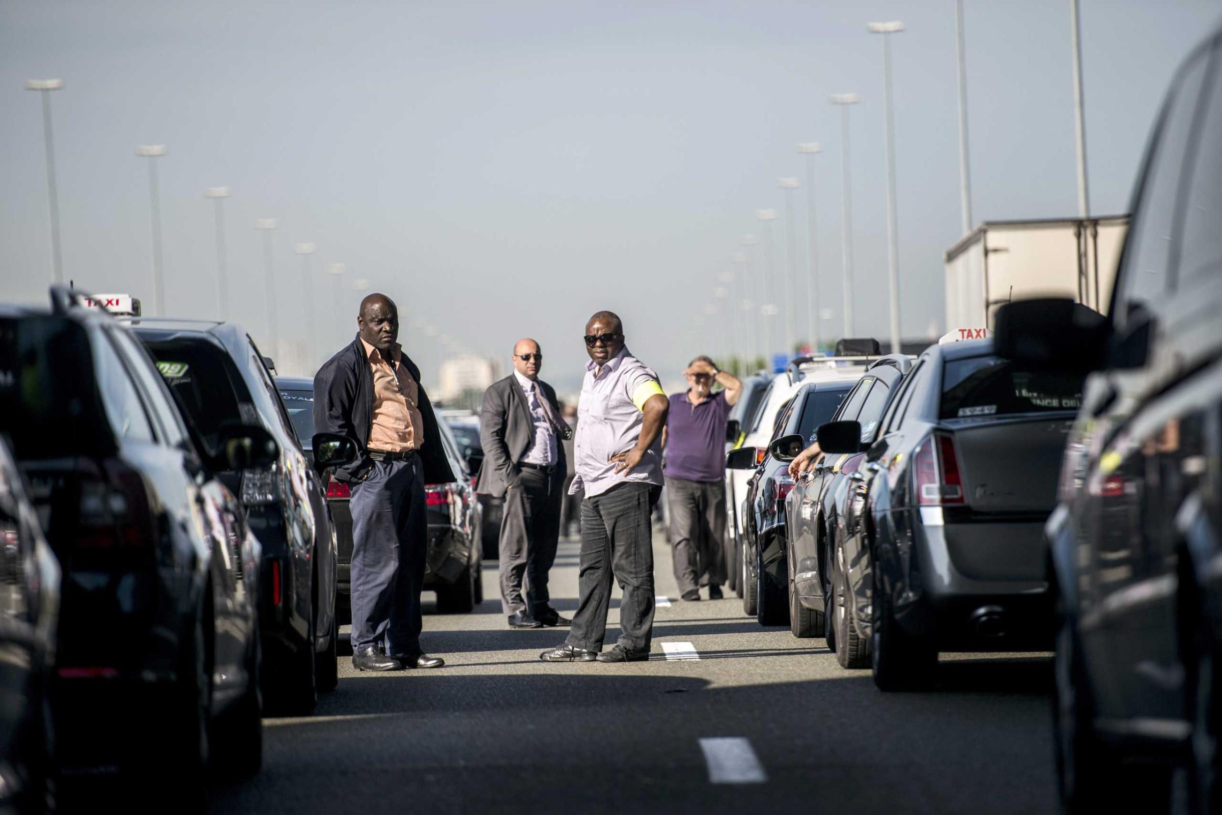Taxis drivers block a highway outside Paris, near Roissy on June 11, 2014, as they take part in a demonstration to protest the growing number of minicabs, known in France as Voitures de Tourisme avec Chauffeurs (VTC).