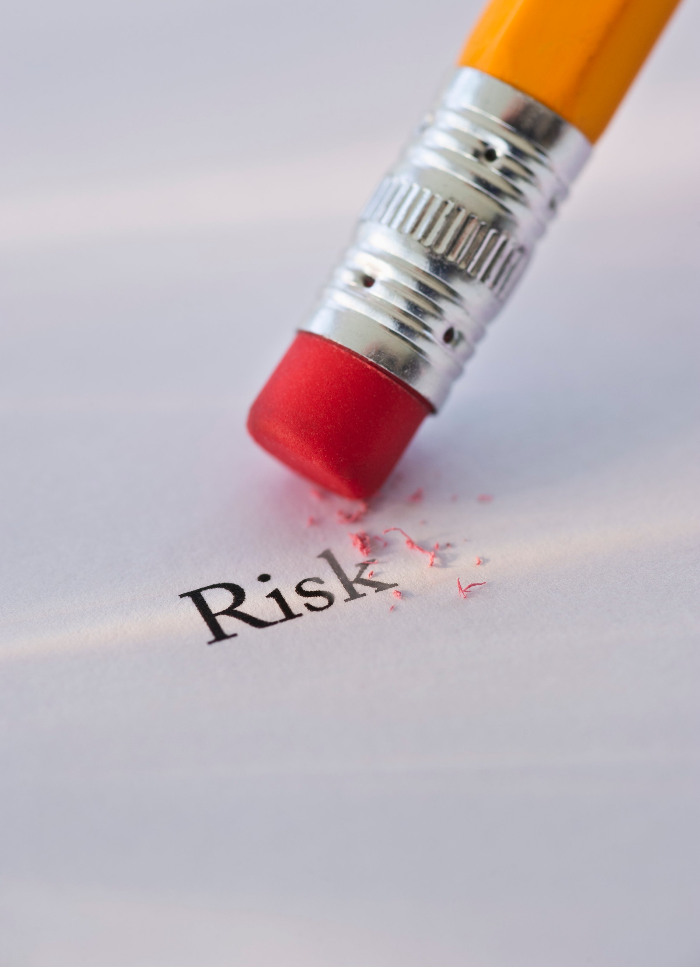 Studio shot of pencil erasing the word risk from piece of paper