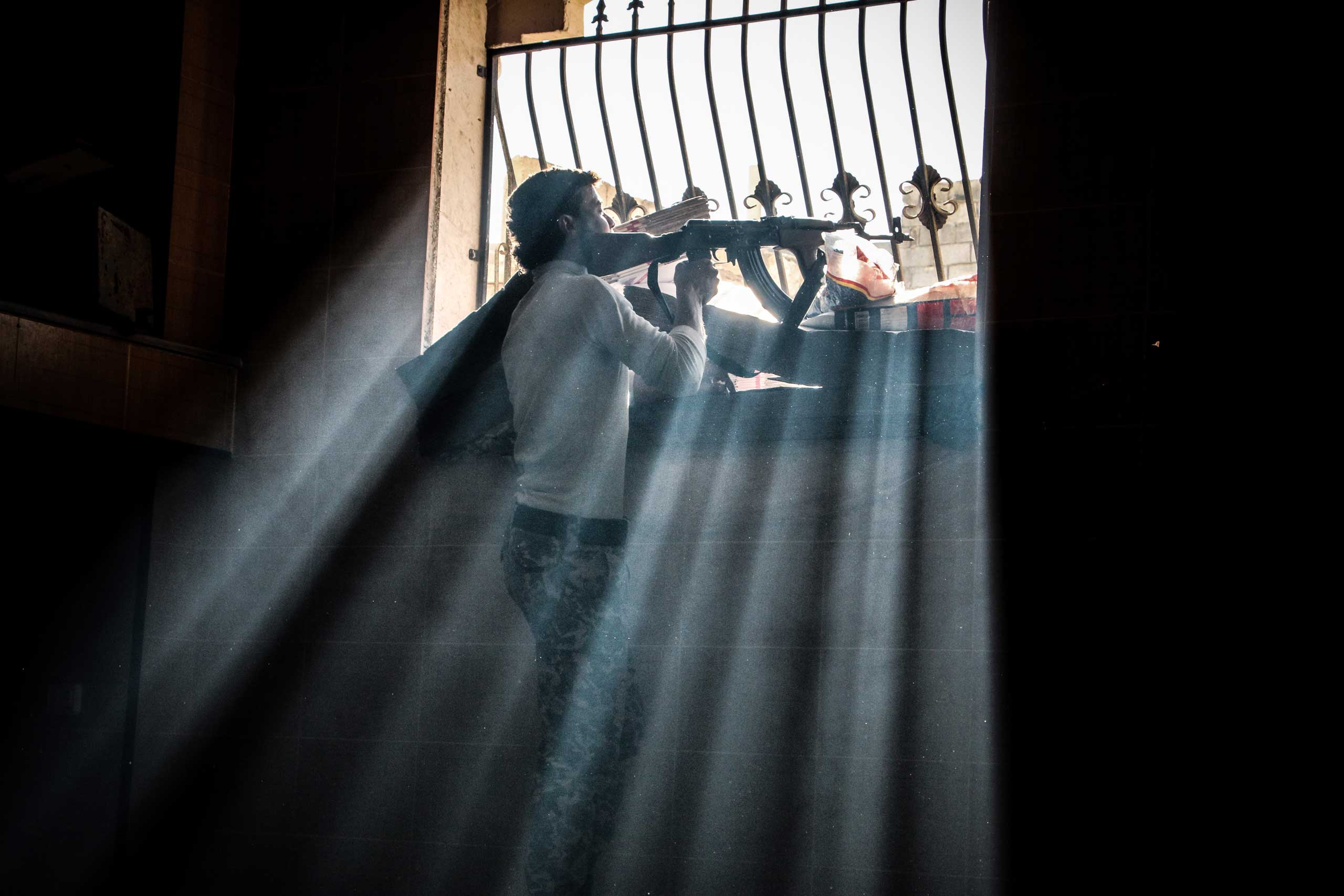 Dec. 17, 2014. Rebels fighter watching the movements of regime forces through a window, in Aleppo, Syria.
