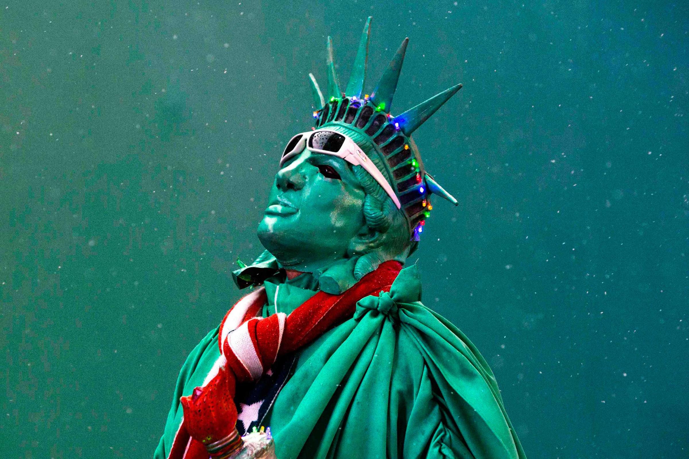 A street performer dressed as the Statue of Liberty stands amongst light snow in Times Square in New York