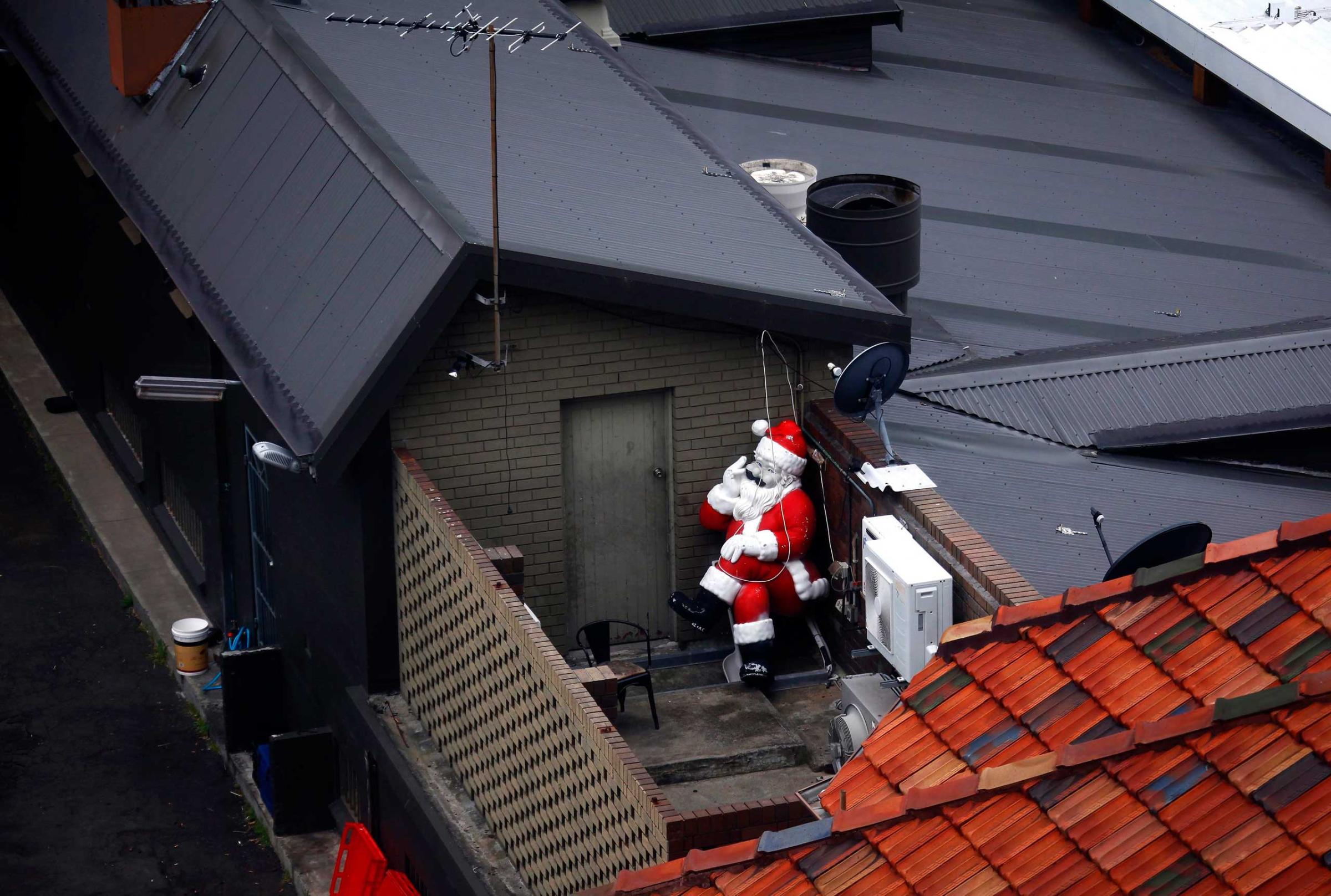 A statue of Santa Claus, that is part of Christmas decorations for a pub, can be seen placed at the back of the building before being put on display in Sydney